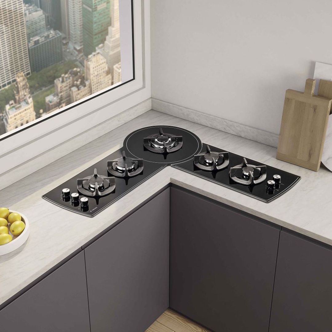 Uma cozinha com fogão a gás e uma tigela de limões na bancada.