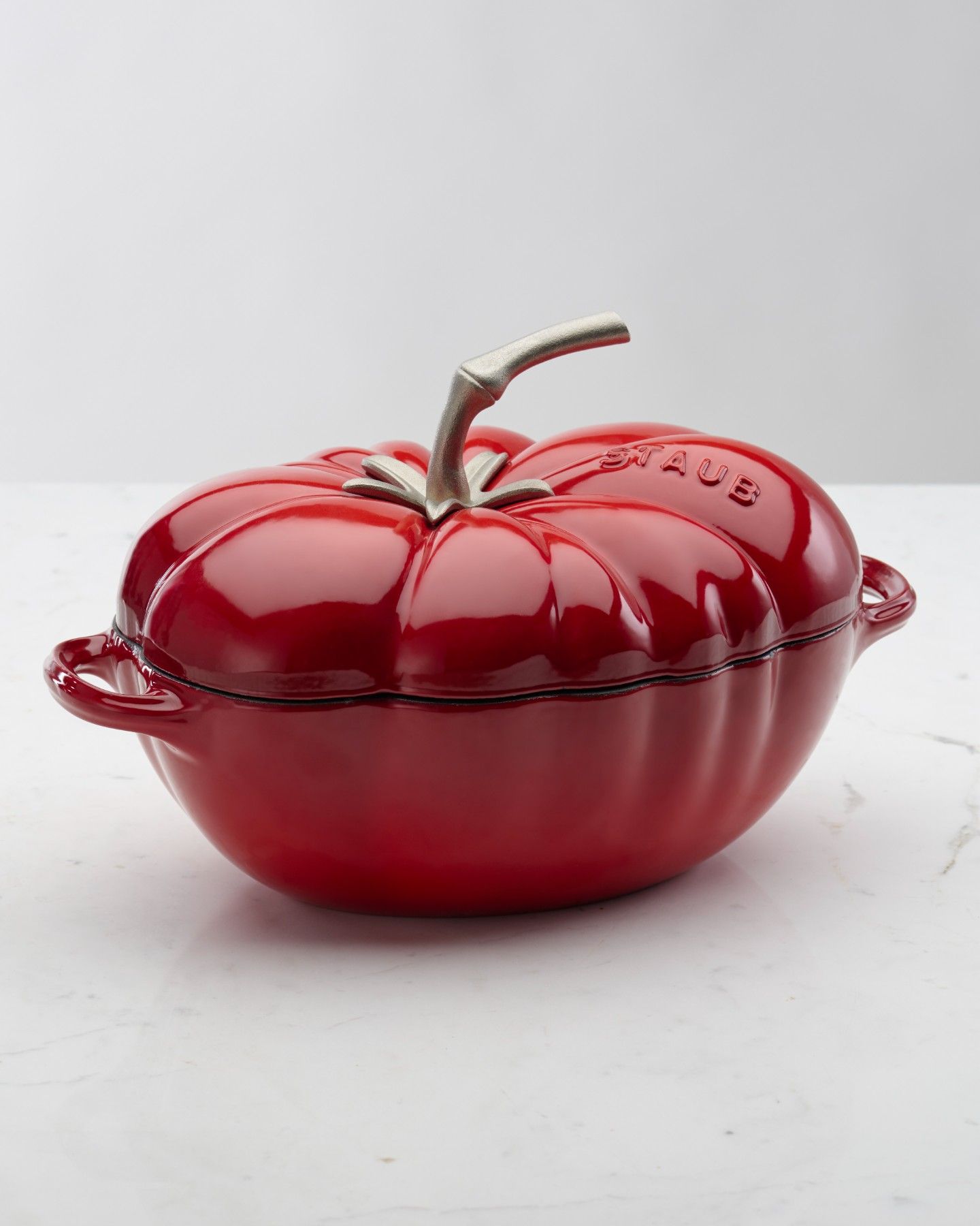 Uma panela vermelha em forma de tomate sobre uma mesa.