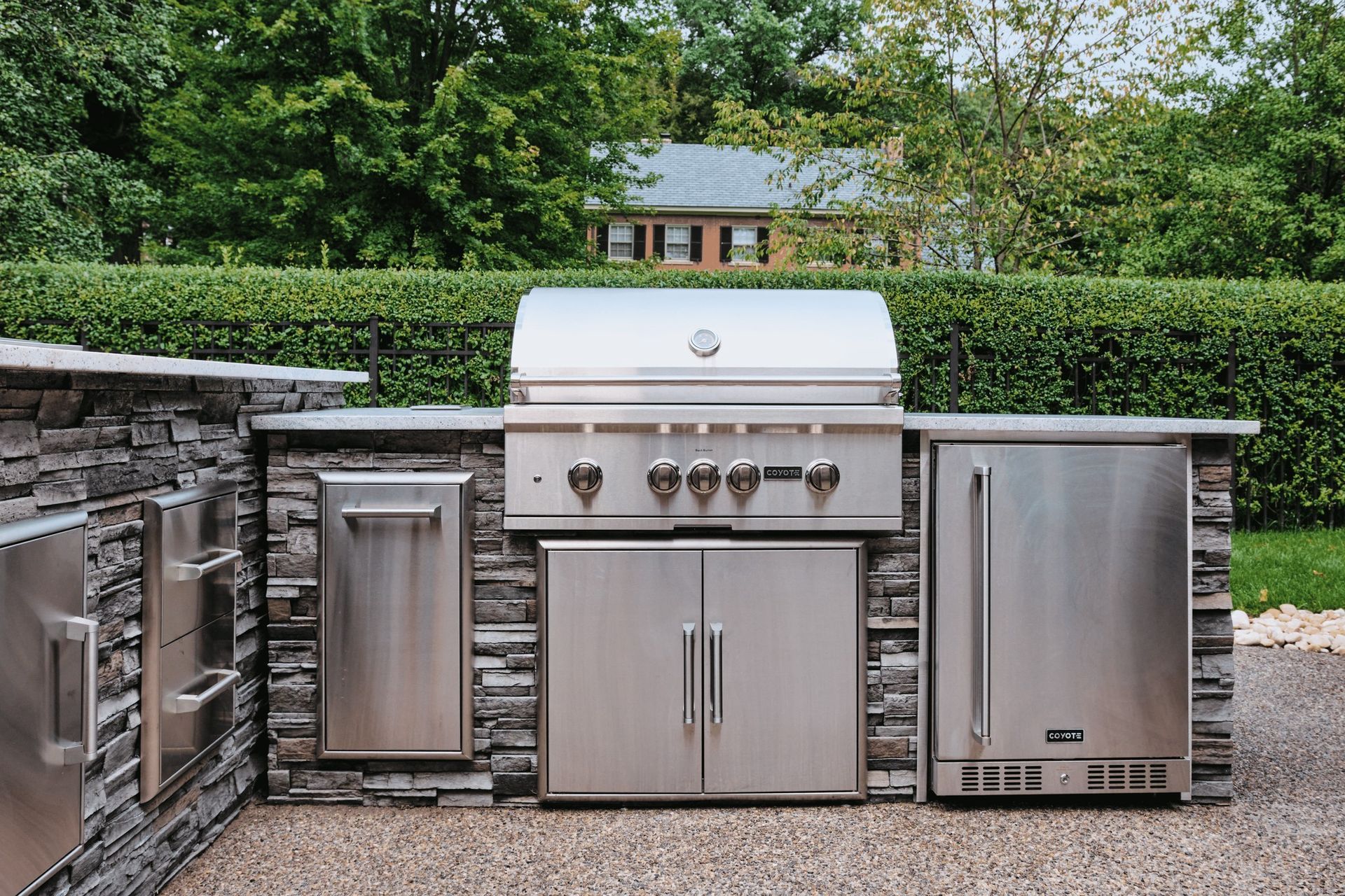 Uma cozinha externa de aço inoxidável com churrasqueira e geladeira