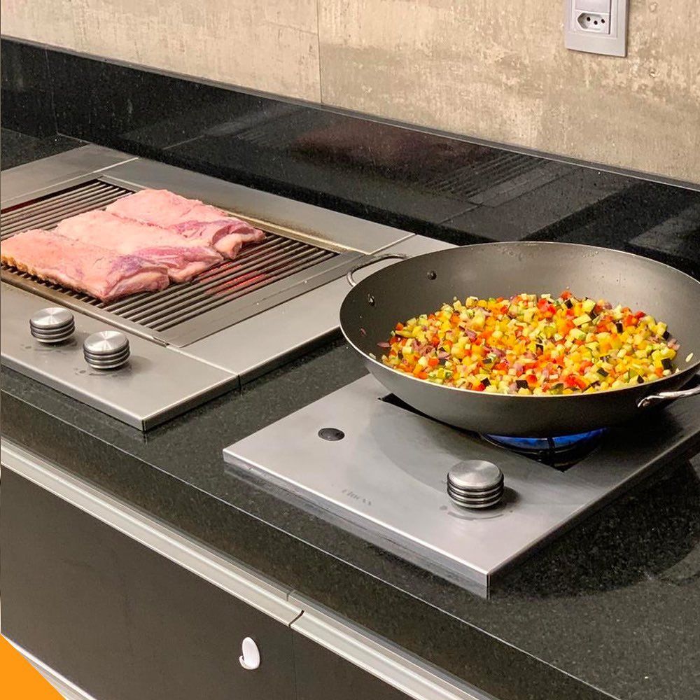 Uma panela de legumes está cozinhando em um fogão ao lado de uma grelha.