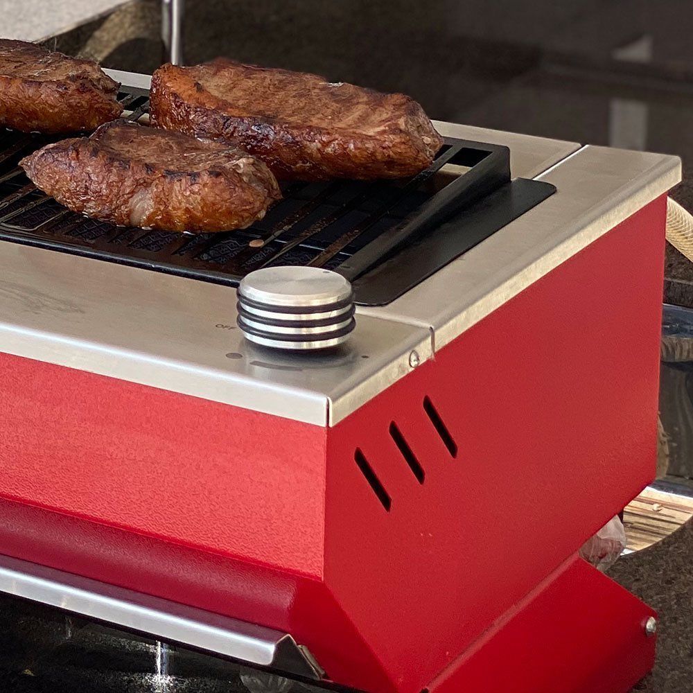 Dois bifes estão cozinhando em uma grelha vermelha