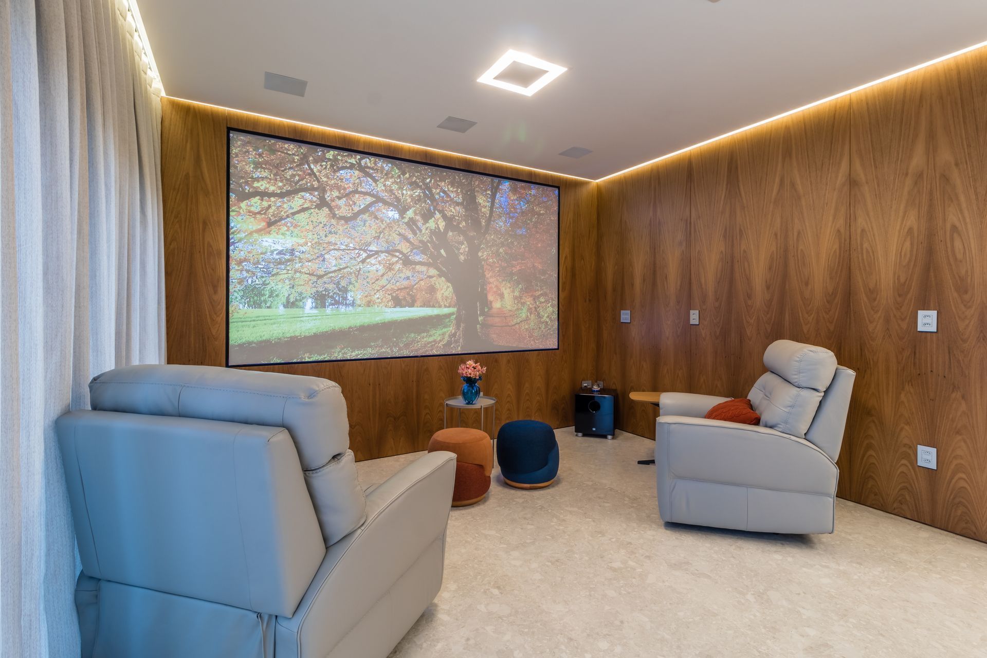 Uma sala de estar com duas cadeiras e uma tela de projeção.