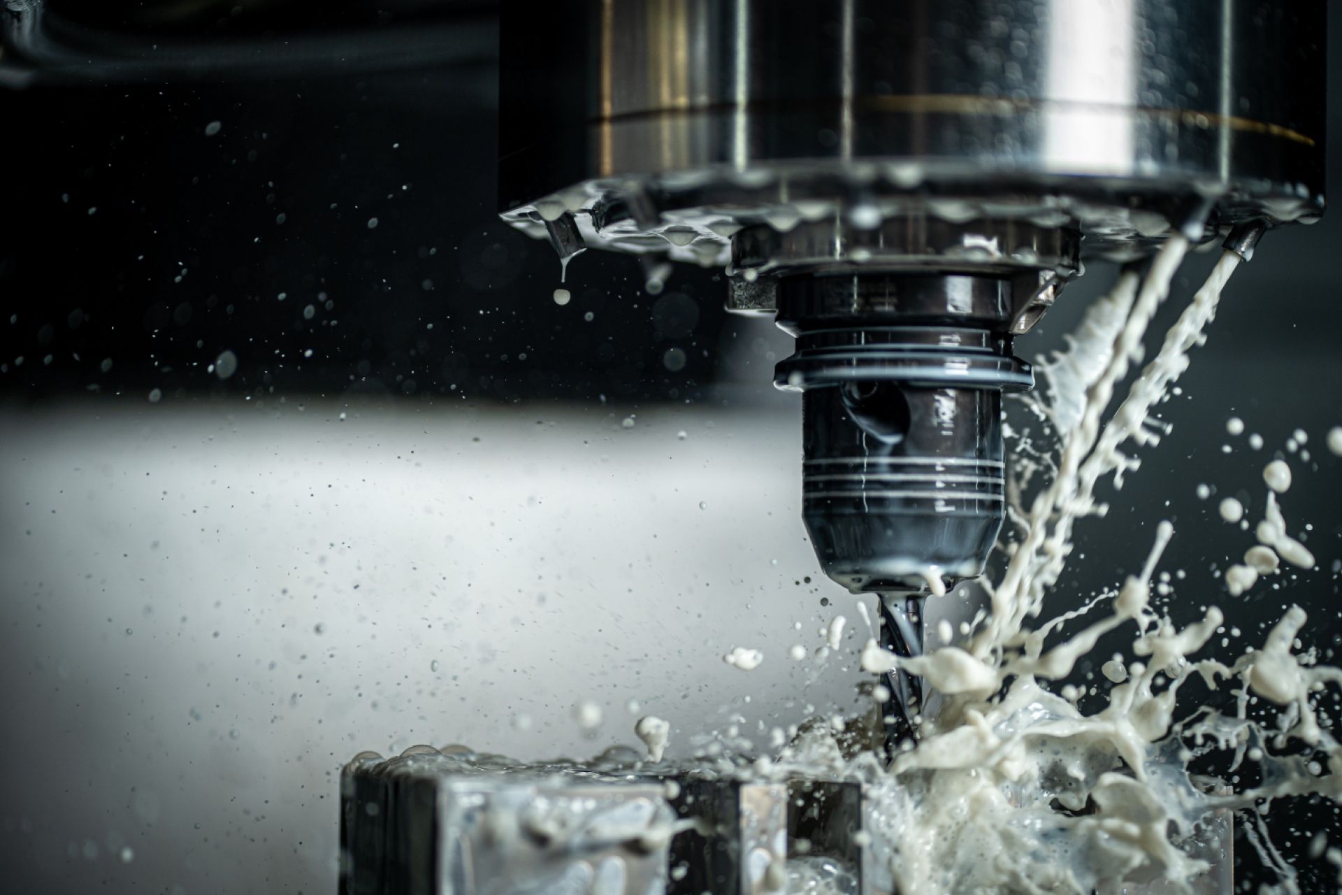 A machine is cutting a piece of metal with liquid coming out of it.