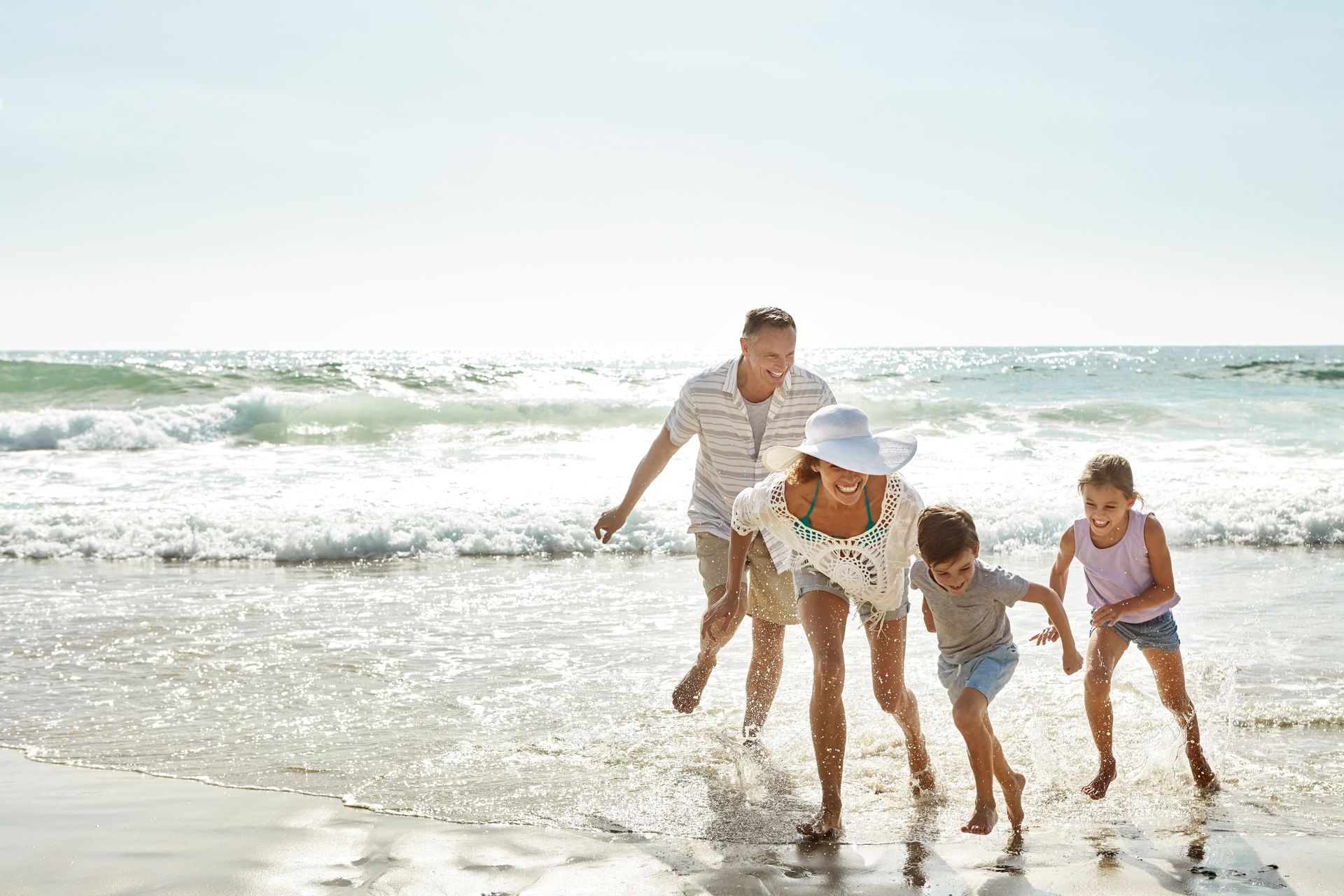 A family is running in the water on the beach.