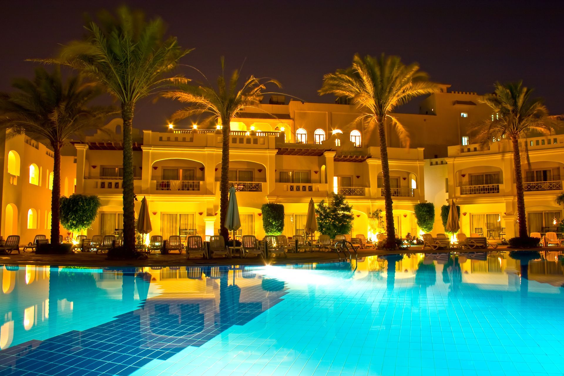 A large swimming pool in front of a hotel at night