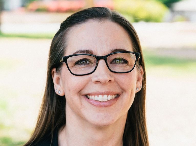 A woman wearing glasses is smiling for the camera.