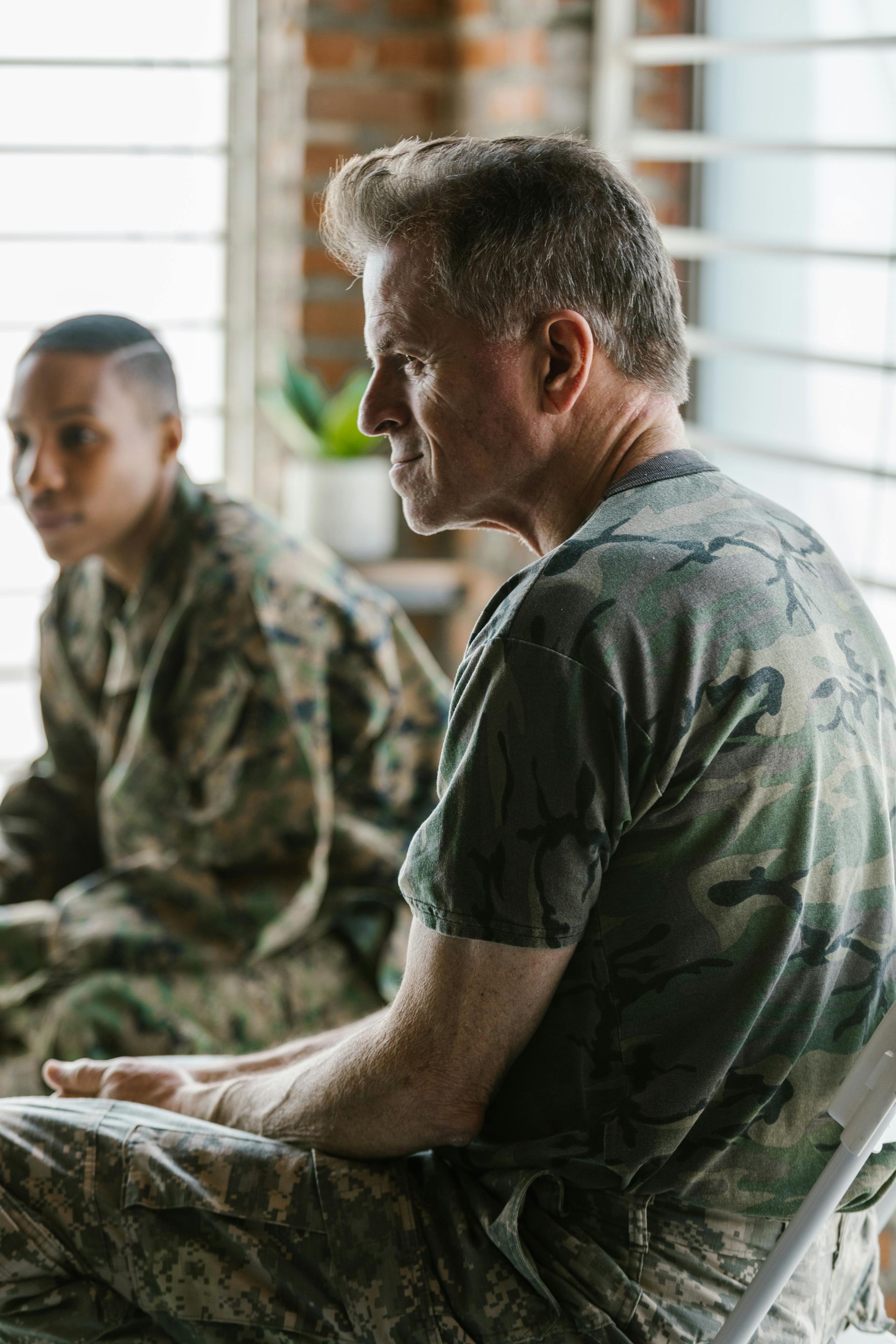 A man in a military uniform is sitting in a chair next to a woman in a military uniform.