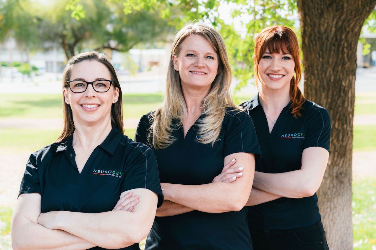 Three women are posing for a picture with their arms crossed in front of a tree.