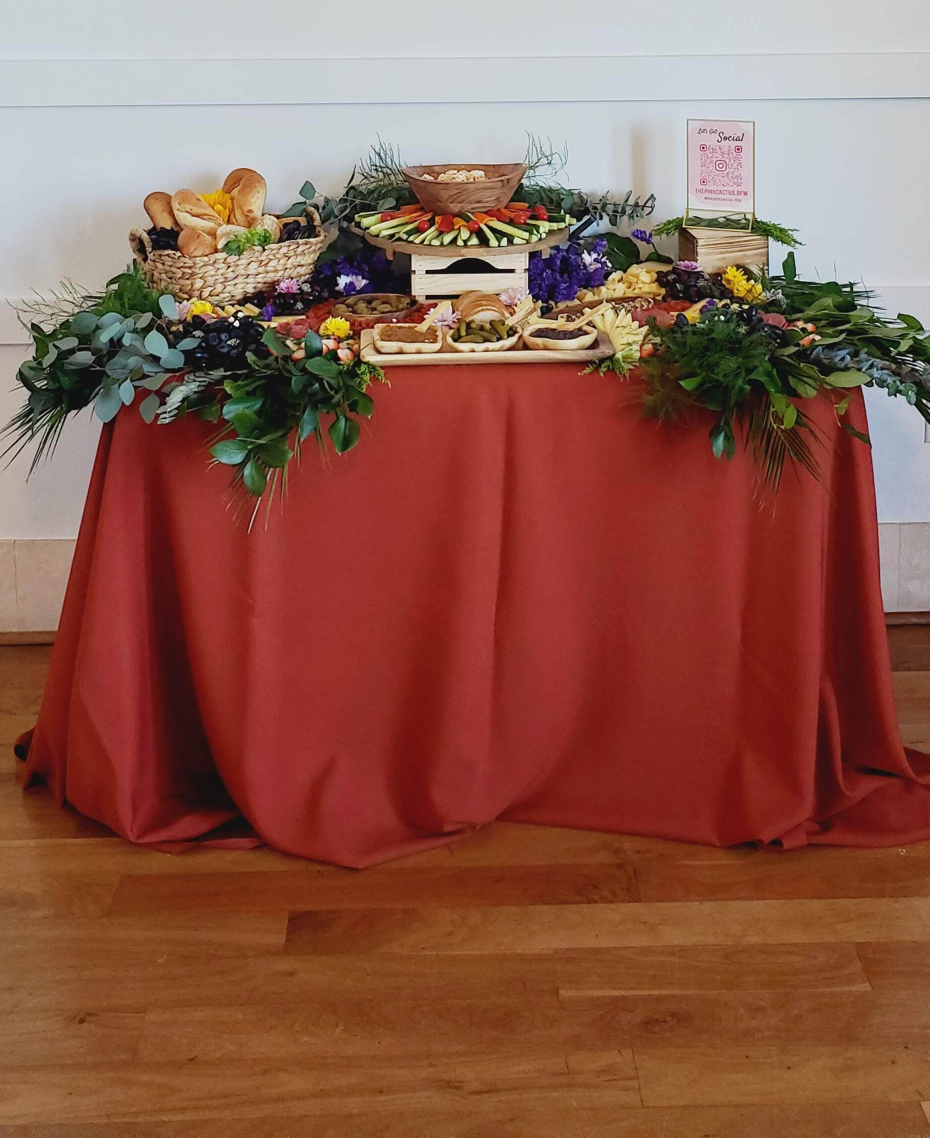 A table with a red tablecloth and a variety of food on it.