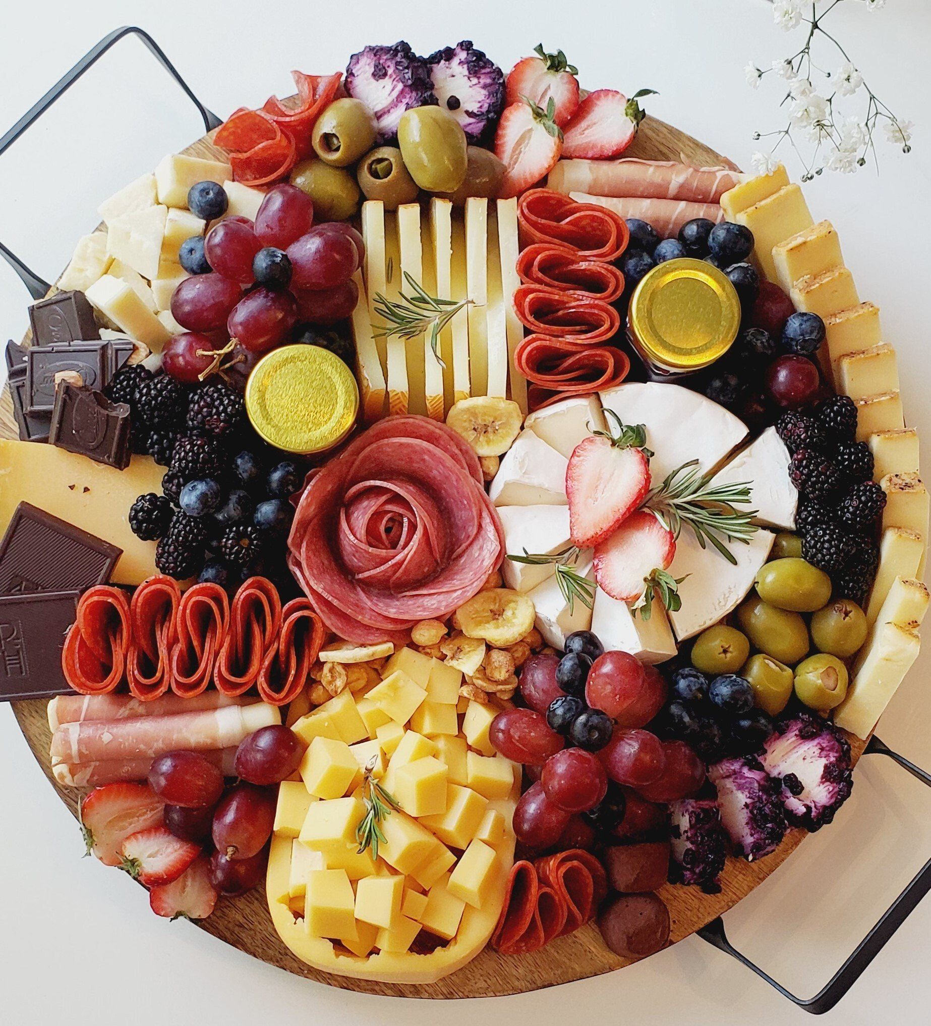 A wooden cutting board filled with fruits and cheeses