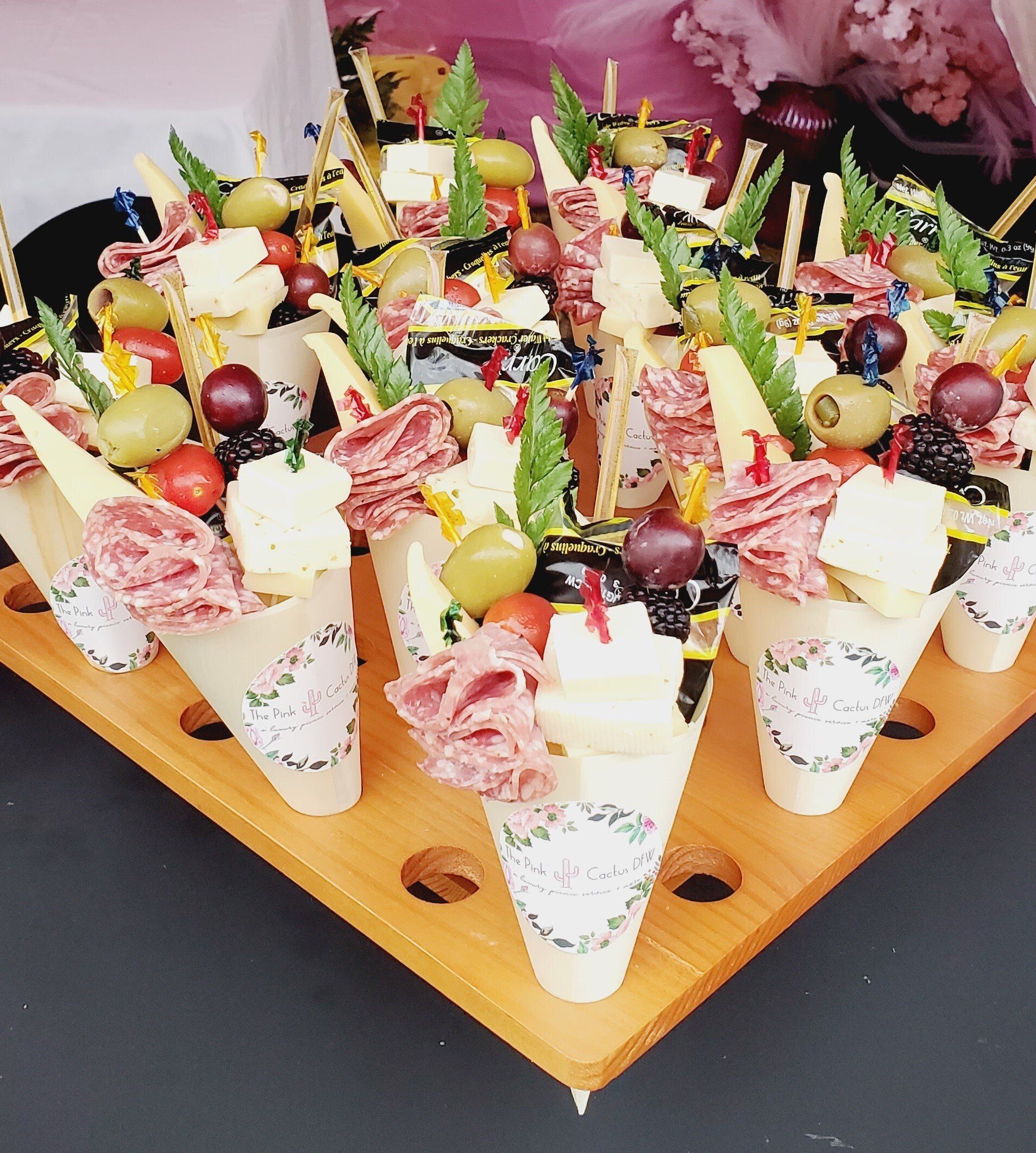 A wooden tray filled with ice cream cones filled with fruit and meat