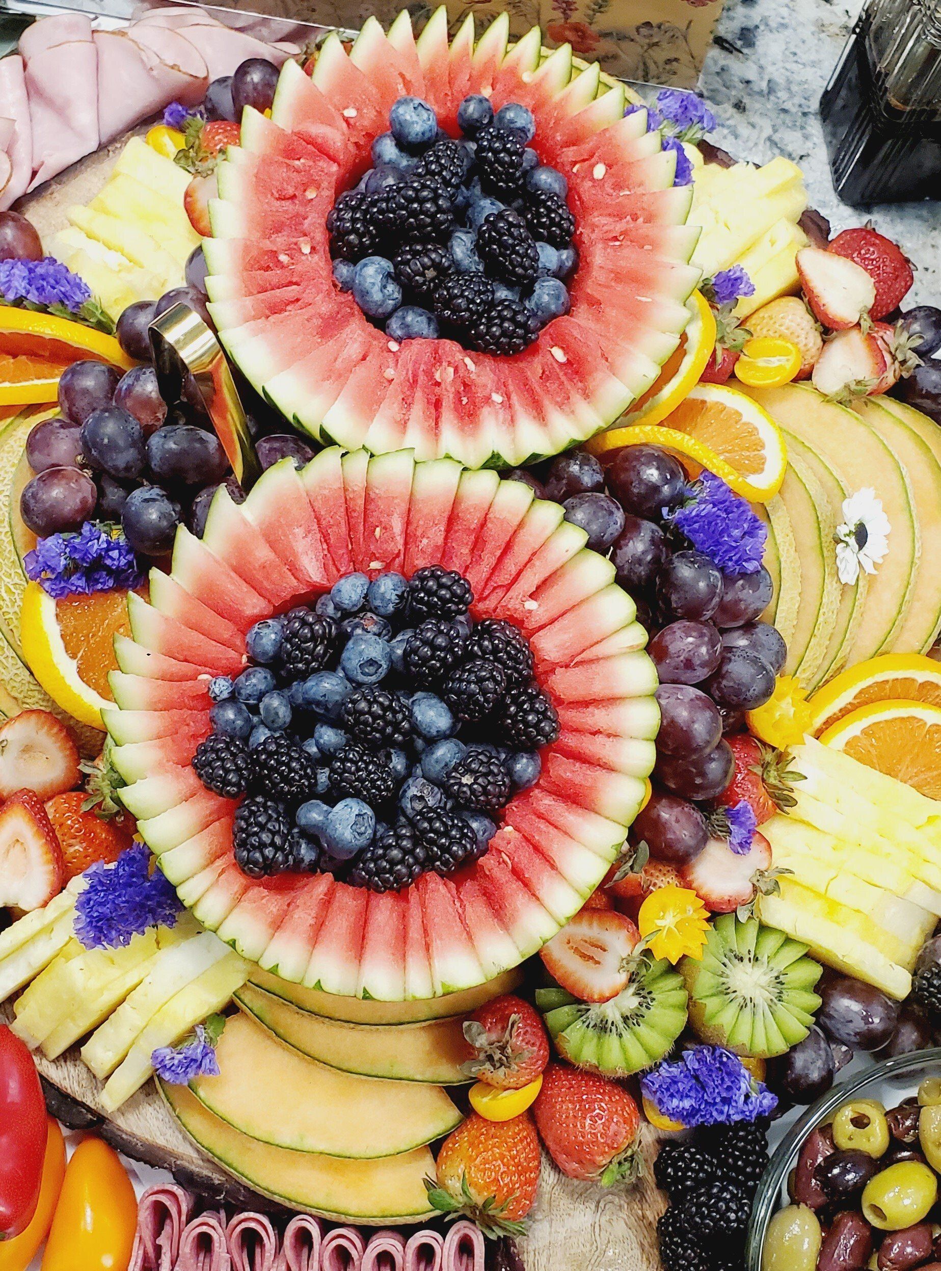 A variety of fruits and vegetables are arranged on a cutting board.