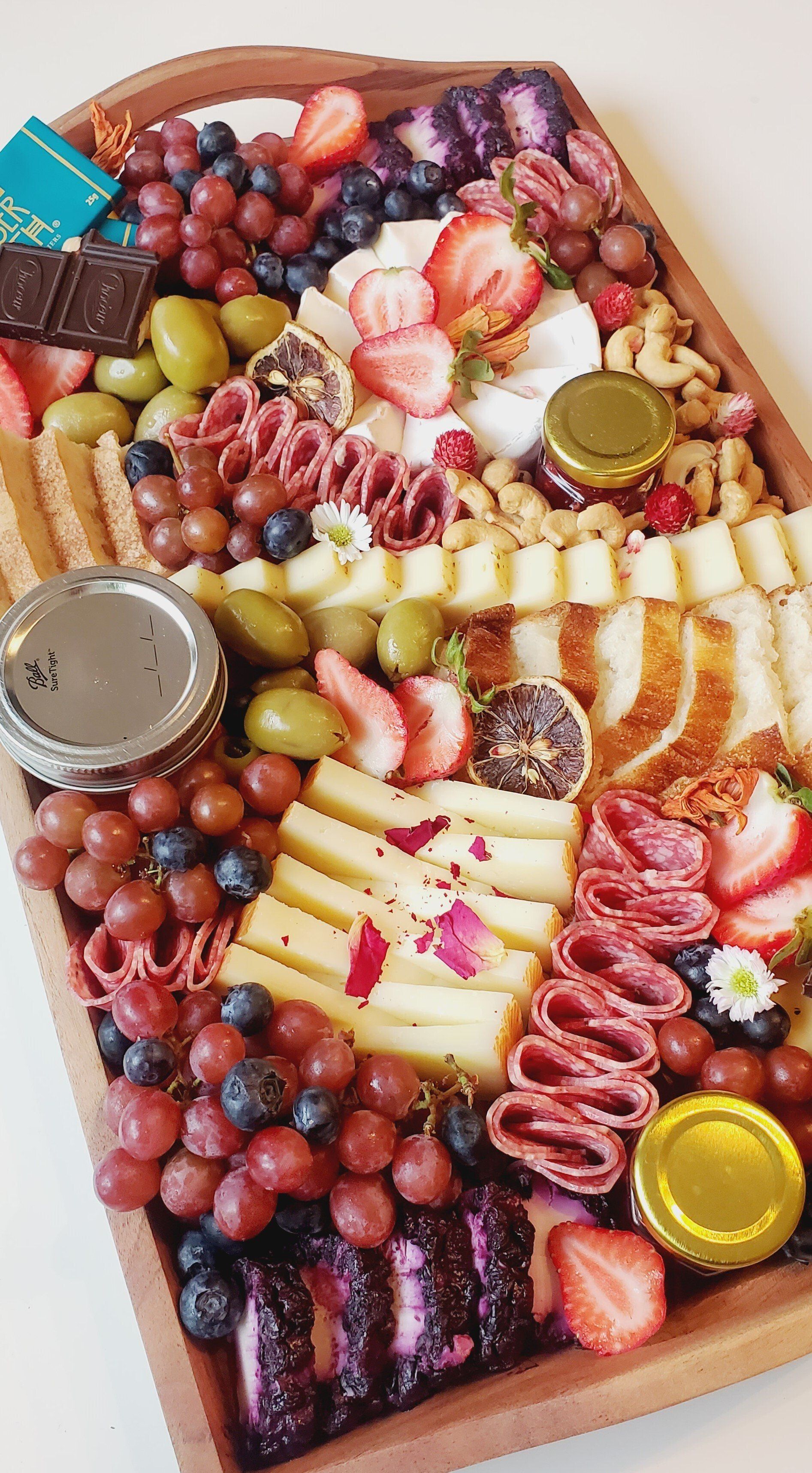 A wooden tray filled with a variety of fruits and cheeses.