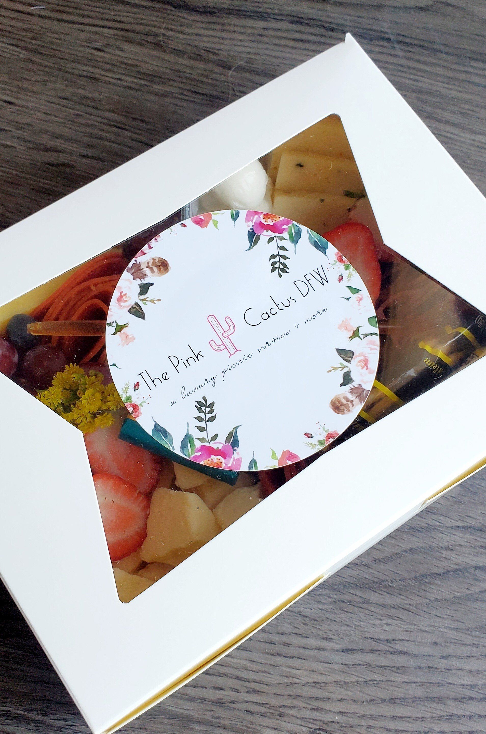 A box of food with a sticker on it is sitting on a wooden table.