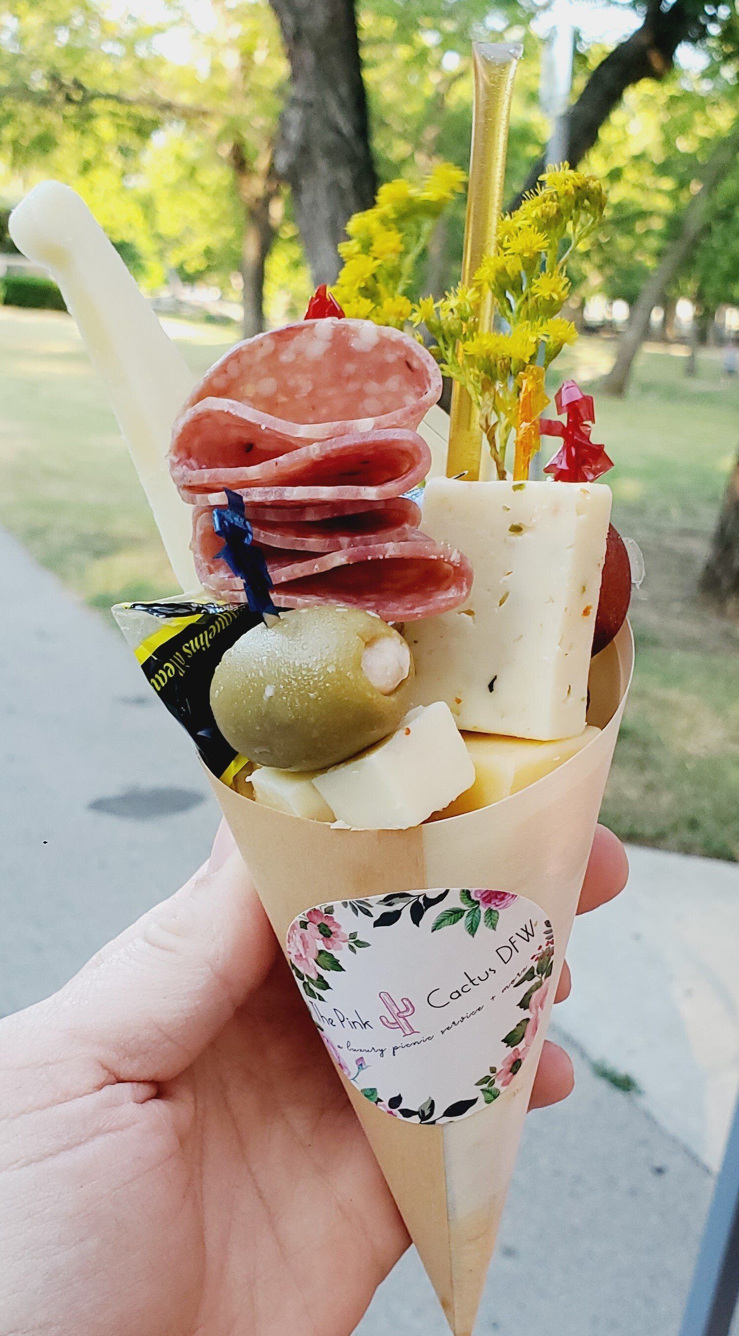 A person is holding a cone filled with meat and cheese.