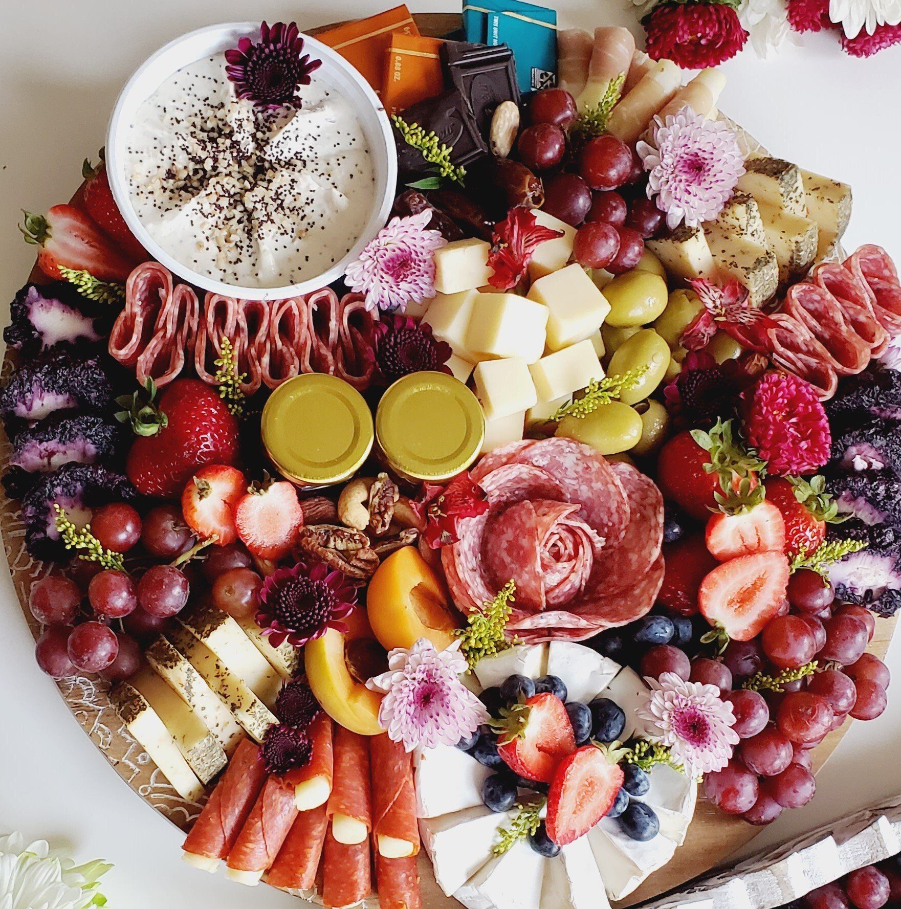 A wooden cutting board filled with a variety of fruits and cheeses