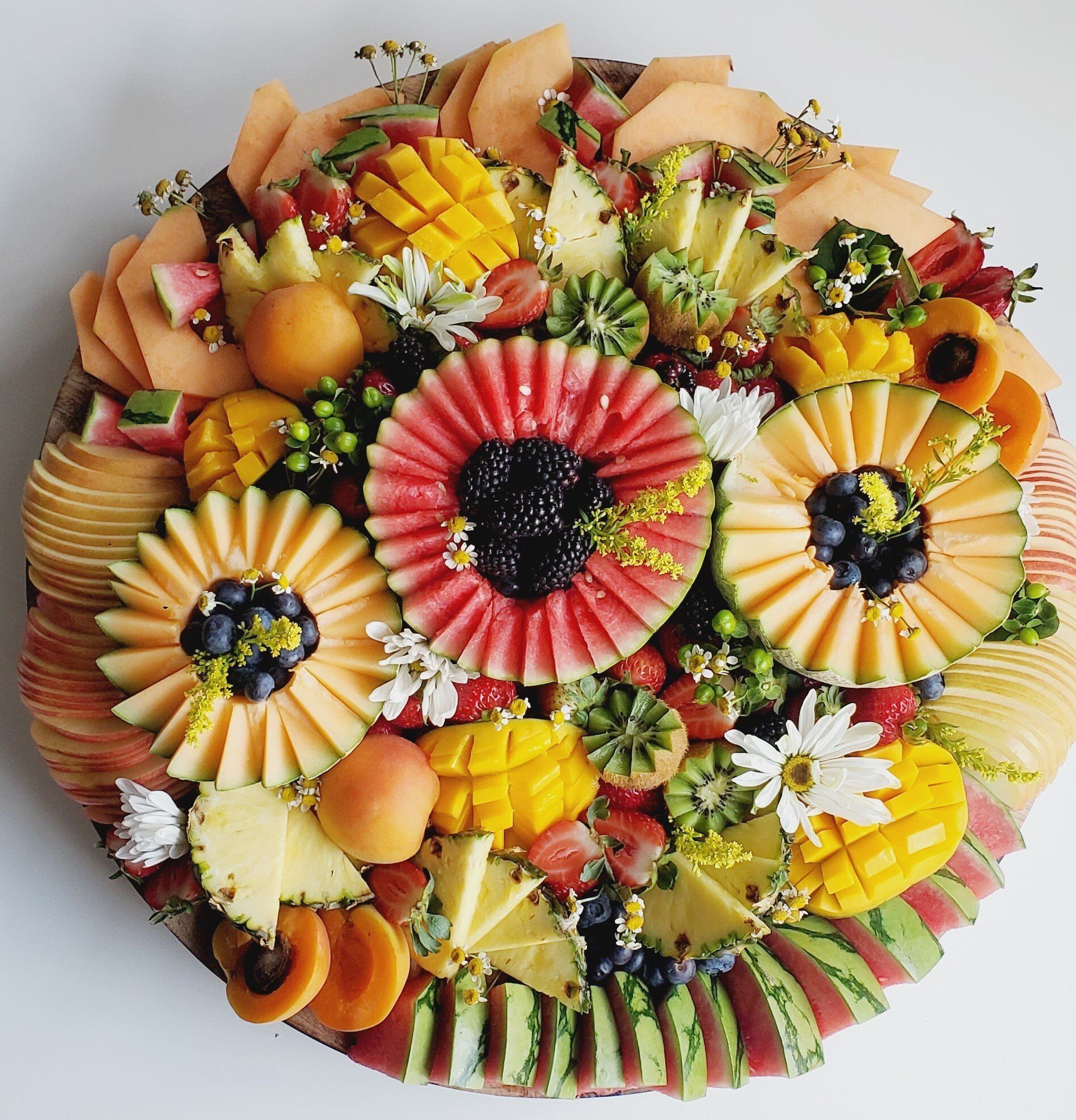 A tray of fruits and vegetables arranged in the shape of flowers