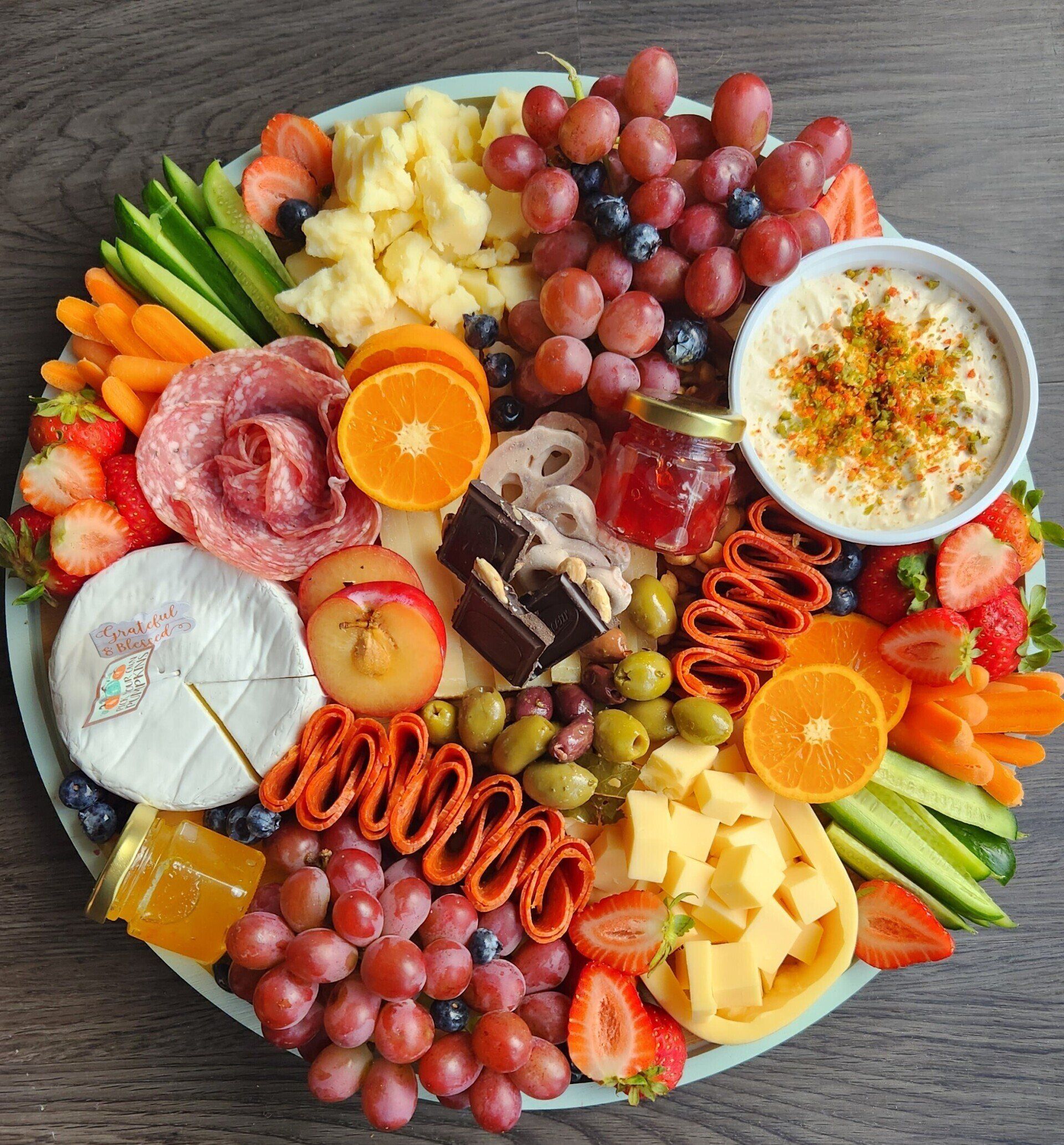 A plate of fruits and vegetables on a wooden table.