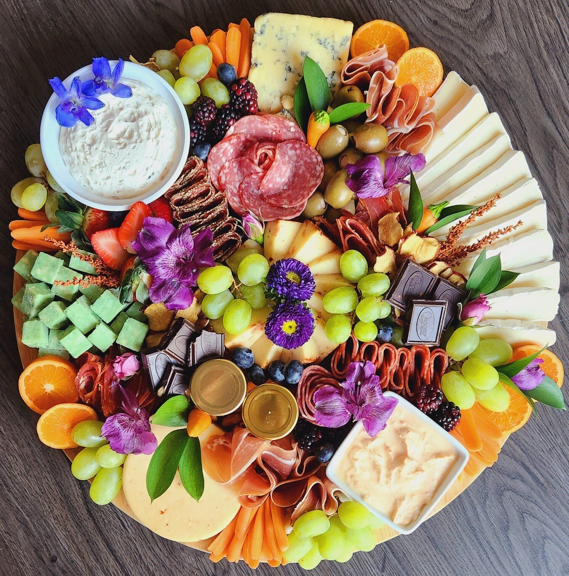 A large platter filled with fruits and vegetables on a wooden table.