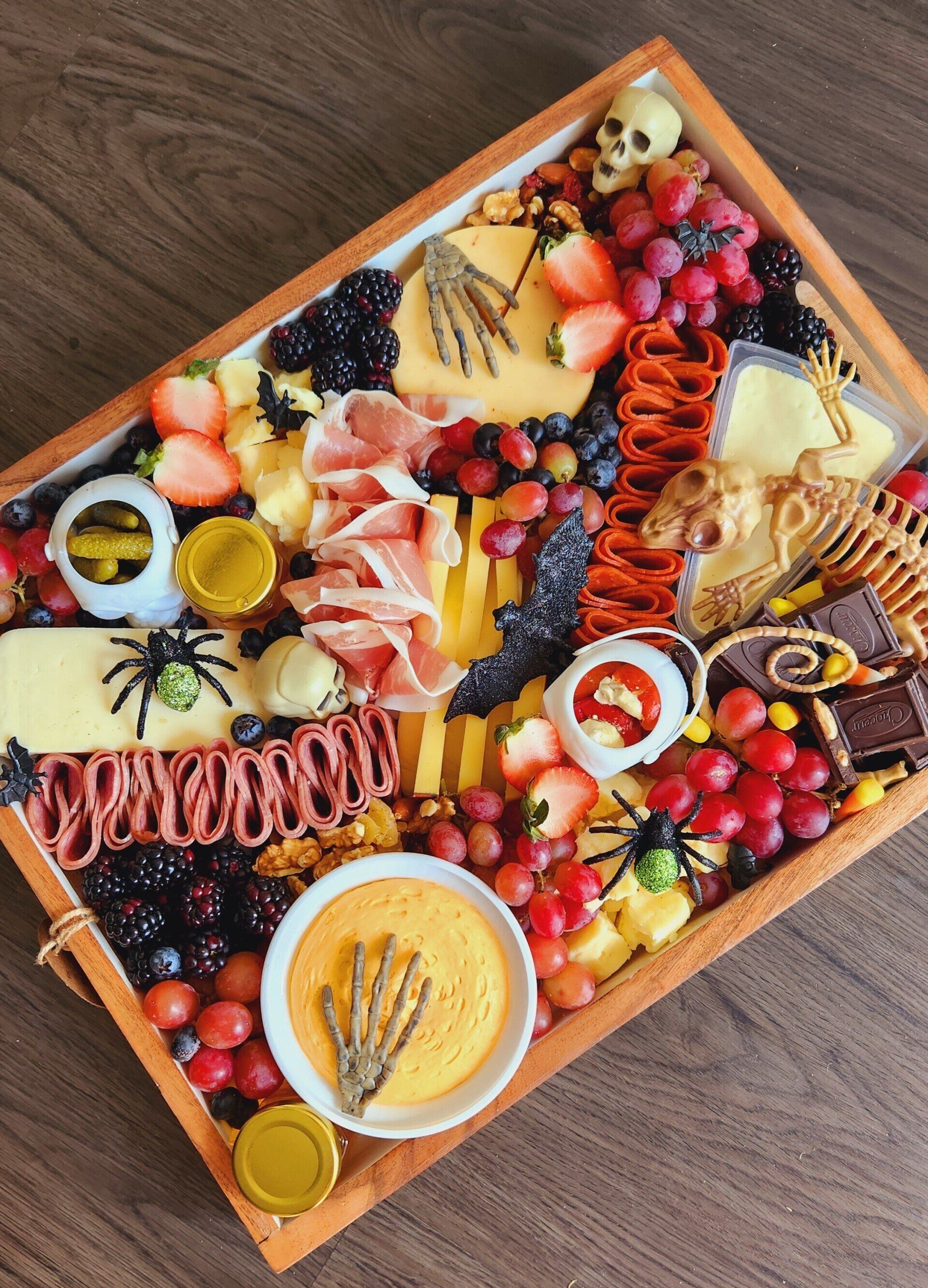 A wooden tray filled with lots of different types of food for halloween.