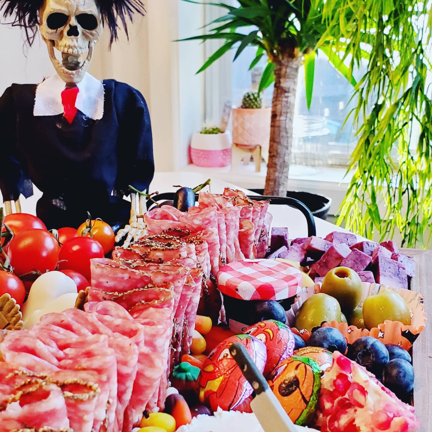 A skeleton is standing in front of a table full of food