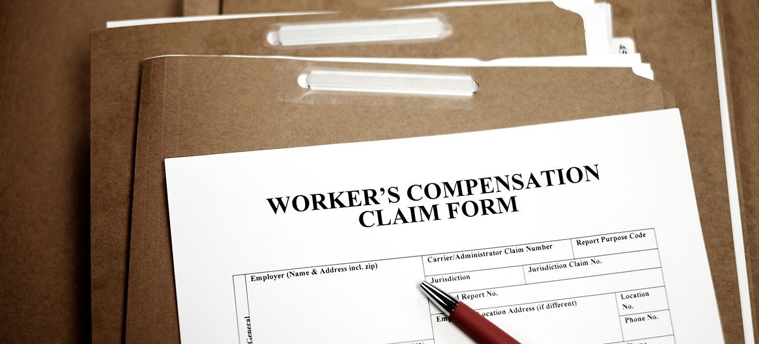 A workers’ compensation claim form placed on top of several brown file folders.
