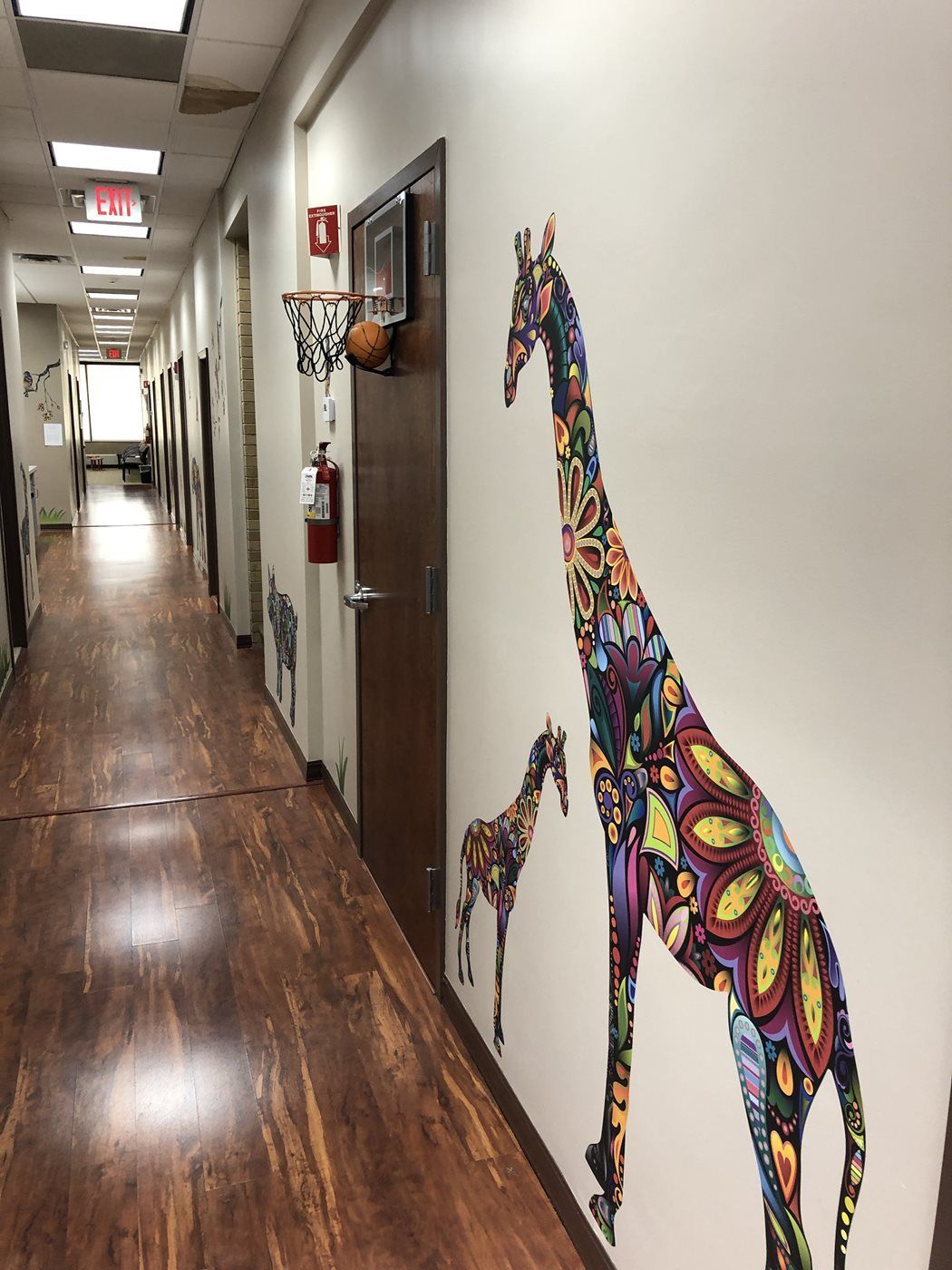 A long hallway with a colorful giraffe on the wall at Advocare Washington Ave Pediatrics in Bergenfield, NJ