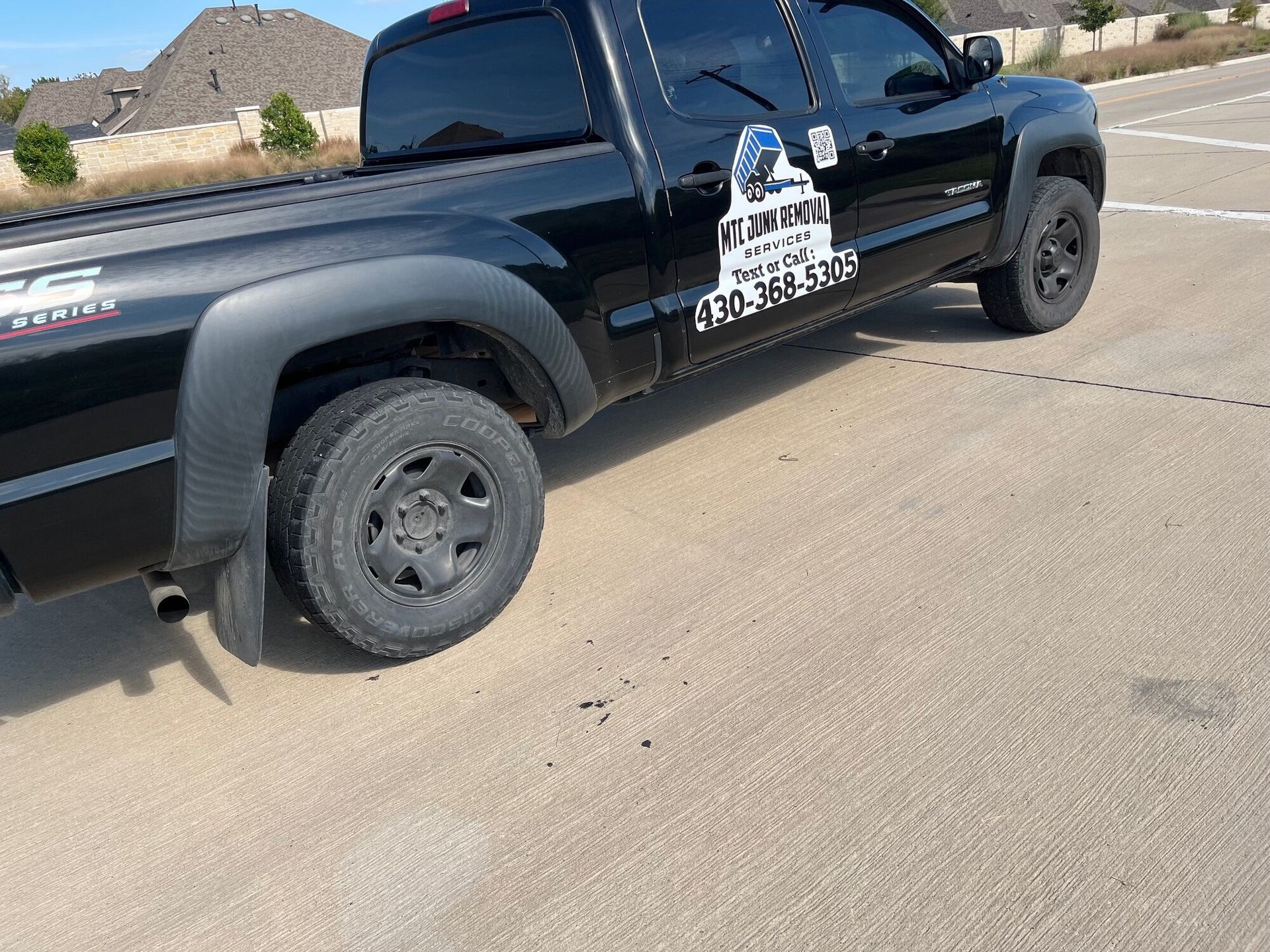 Black pickup truck with business logo on side, parked on asphalt.