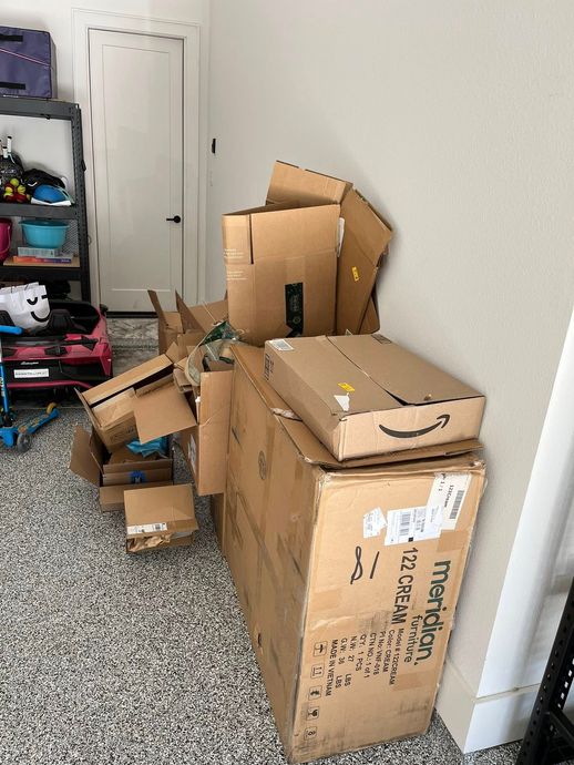 Cardboard boxes piled in a garage, including an Amazon box with a smiley face.