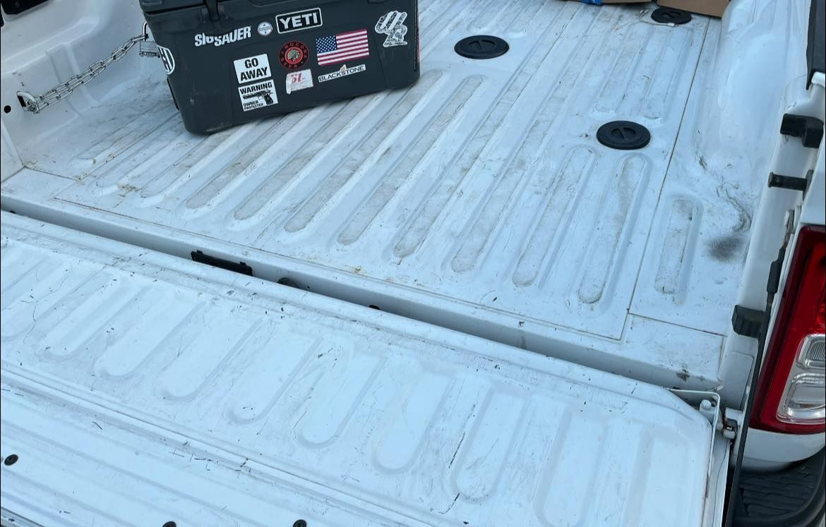 Empty white pickup truck bed with a black toolbox near the cab.