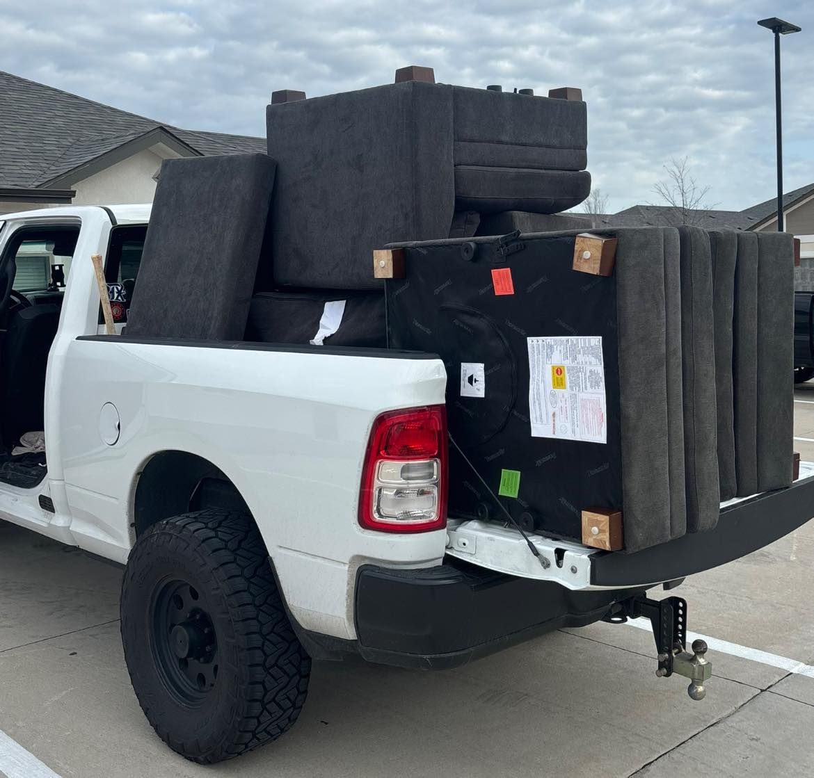 White pickup truck loaded with large black foam blocks in a parking lot