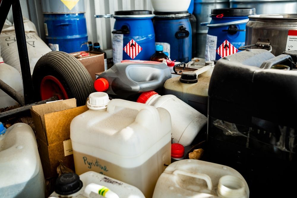 A cluttered storage space filled with various containers, some labeled with hazard symbols.