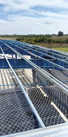 Paneles solares siendo instalados en un techo, con estructura metálica y malla protectora.