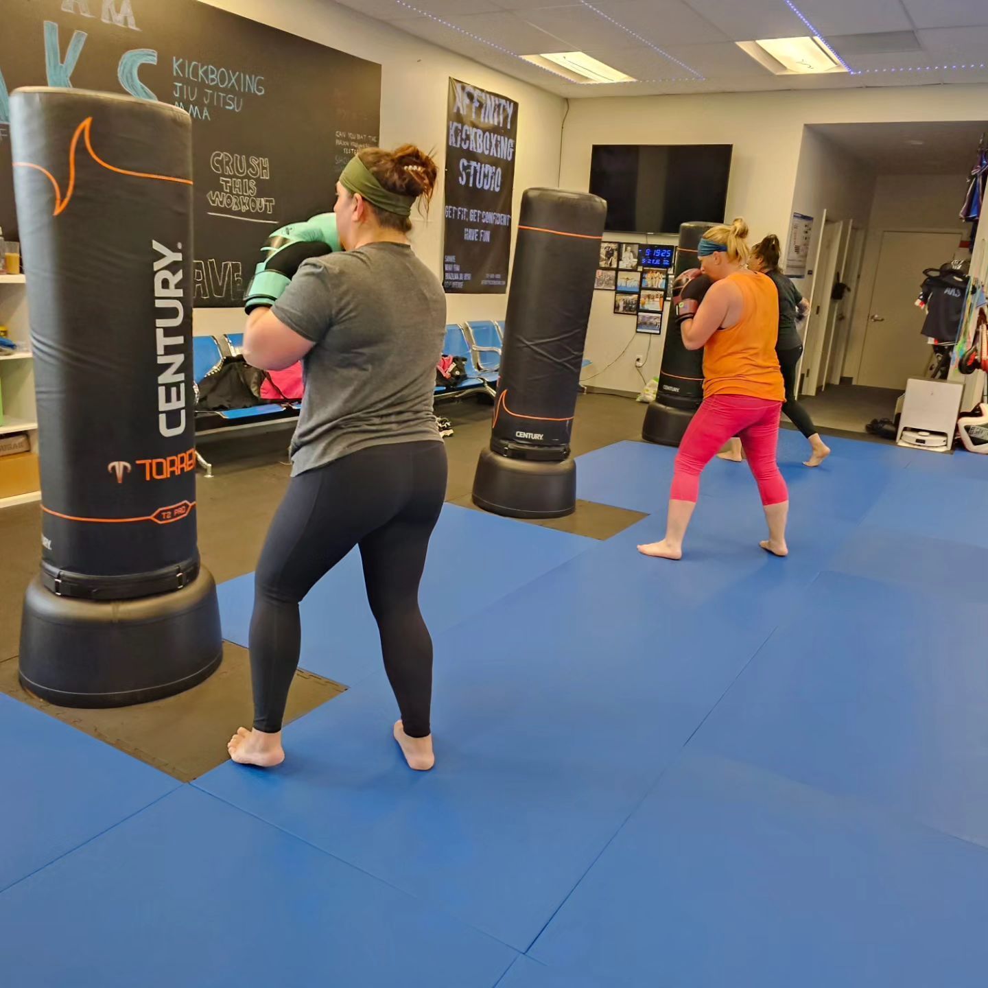 A woman is standing in front of a century boxing bag