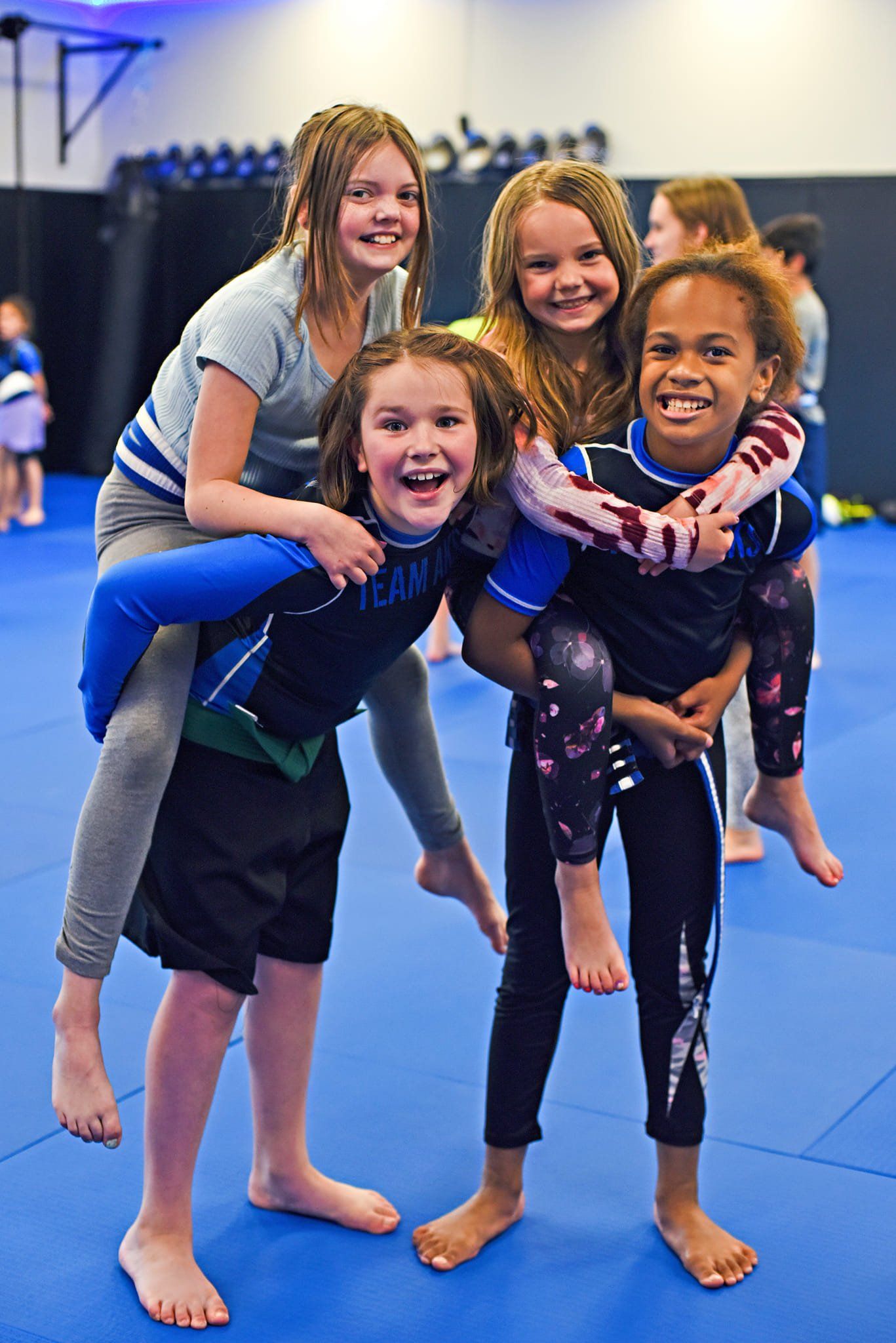 A group of young girls are standing next to each other on a blue mat.