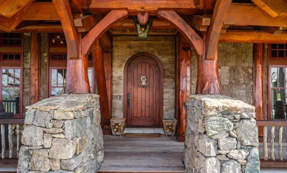The front door of a house with a wooden archway and stone pillars.