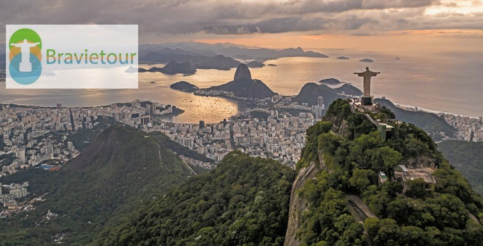 Estátua do Cristo Redentor com vista para o Rio de Janeiro, com a cidade, as montanhas e o mar ao fundo; logotipo da Bravietour.