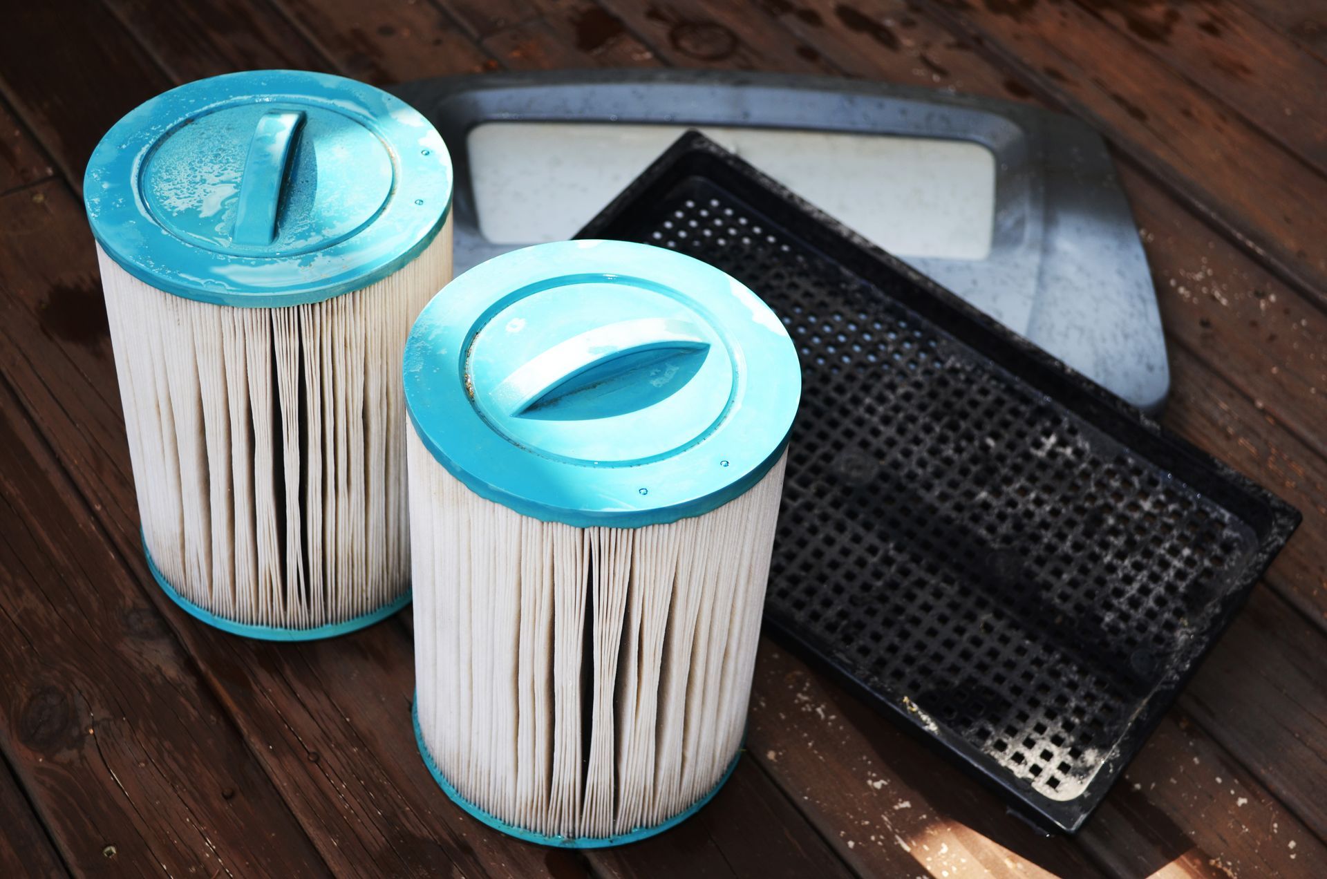 Two dirty pool filters are sitting on a wooden table