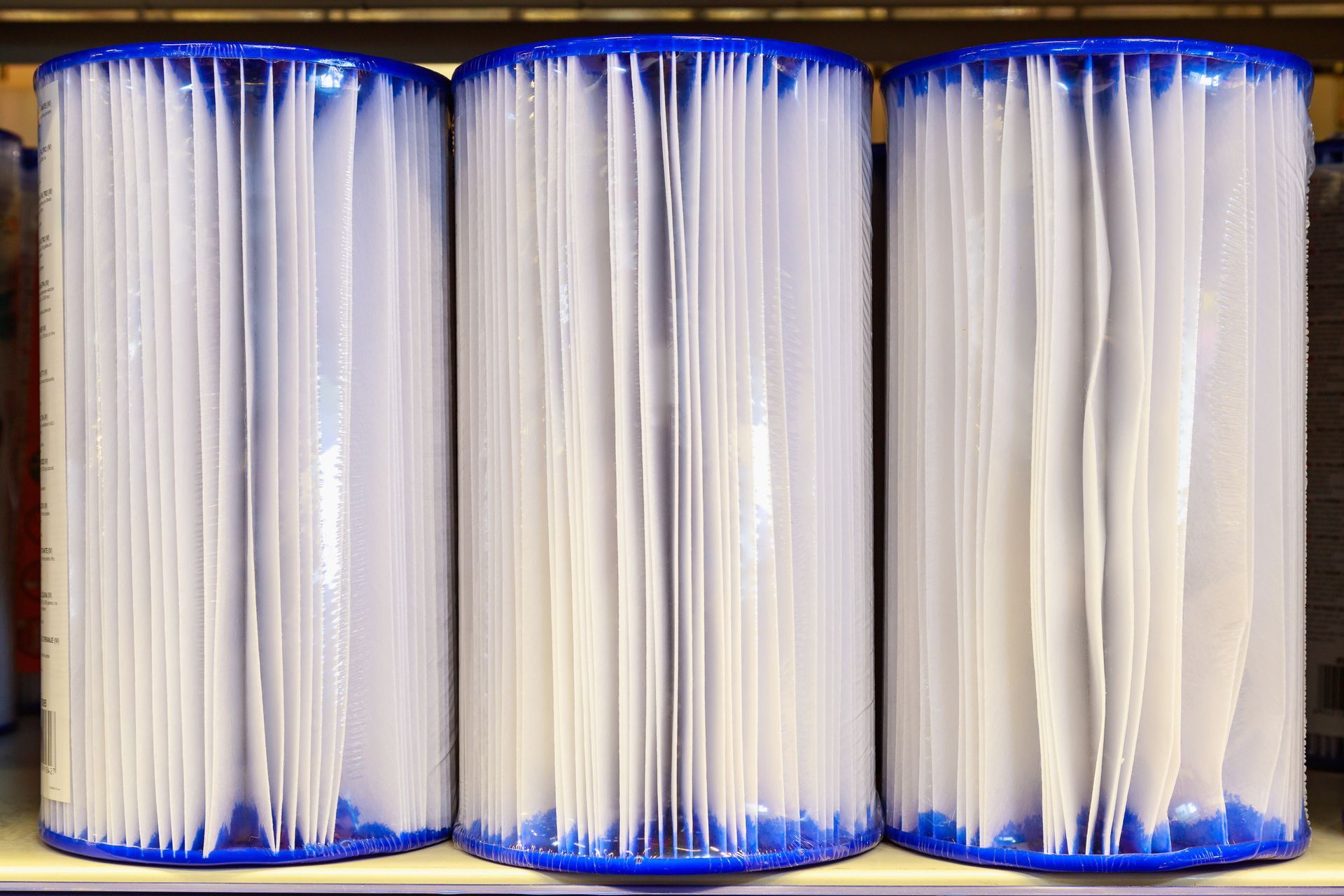 Three pool filters are lined up on a shelf.