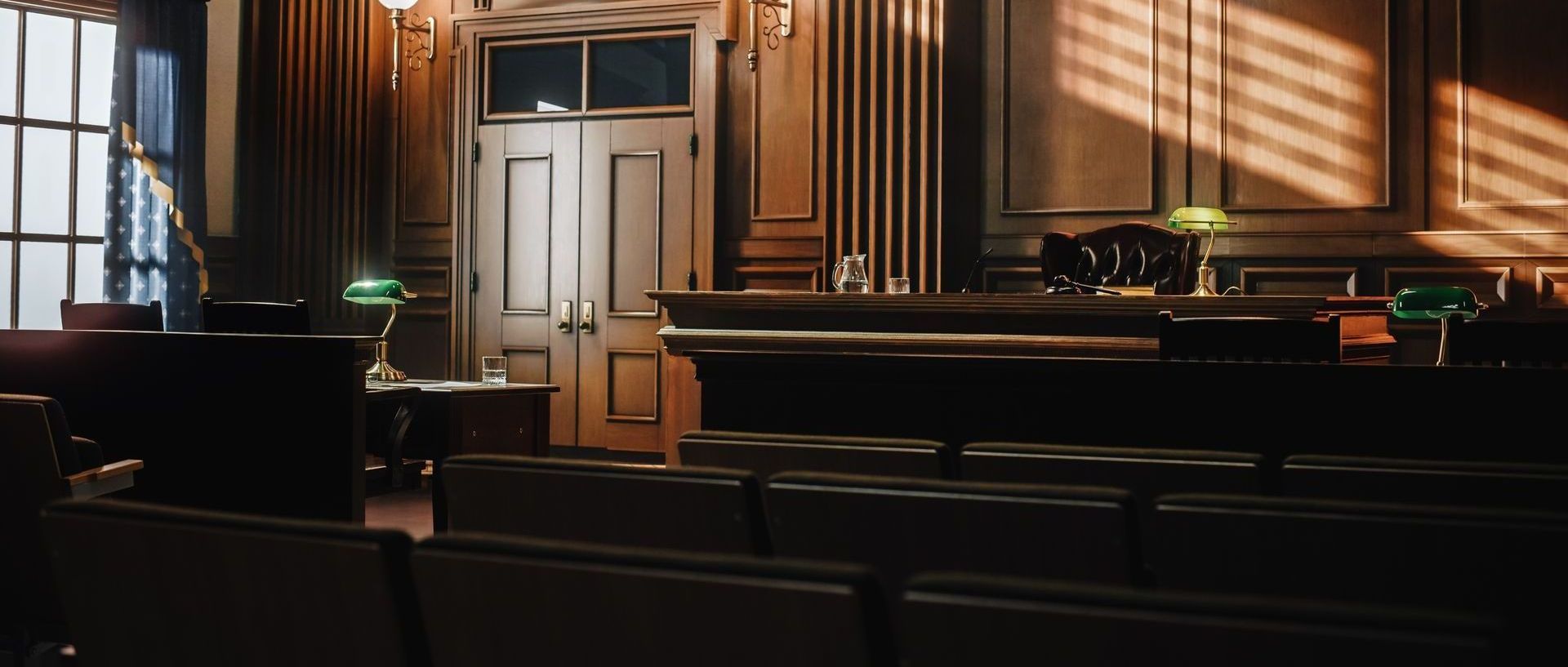 An empty courtroom with rows of chairs and a judge 's bench.