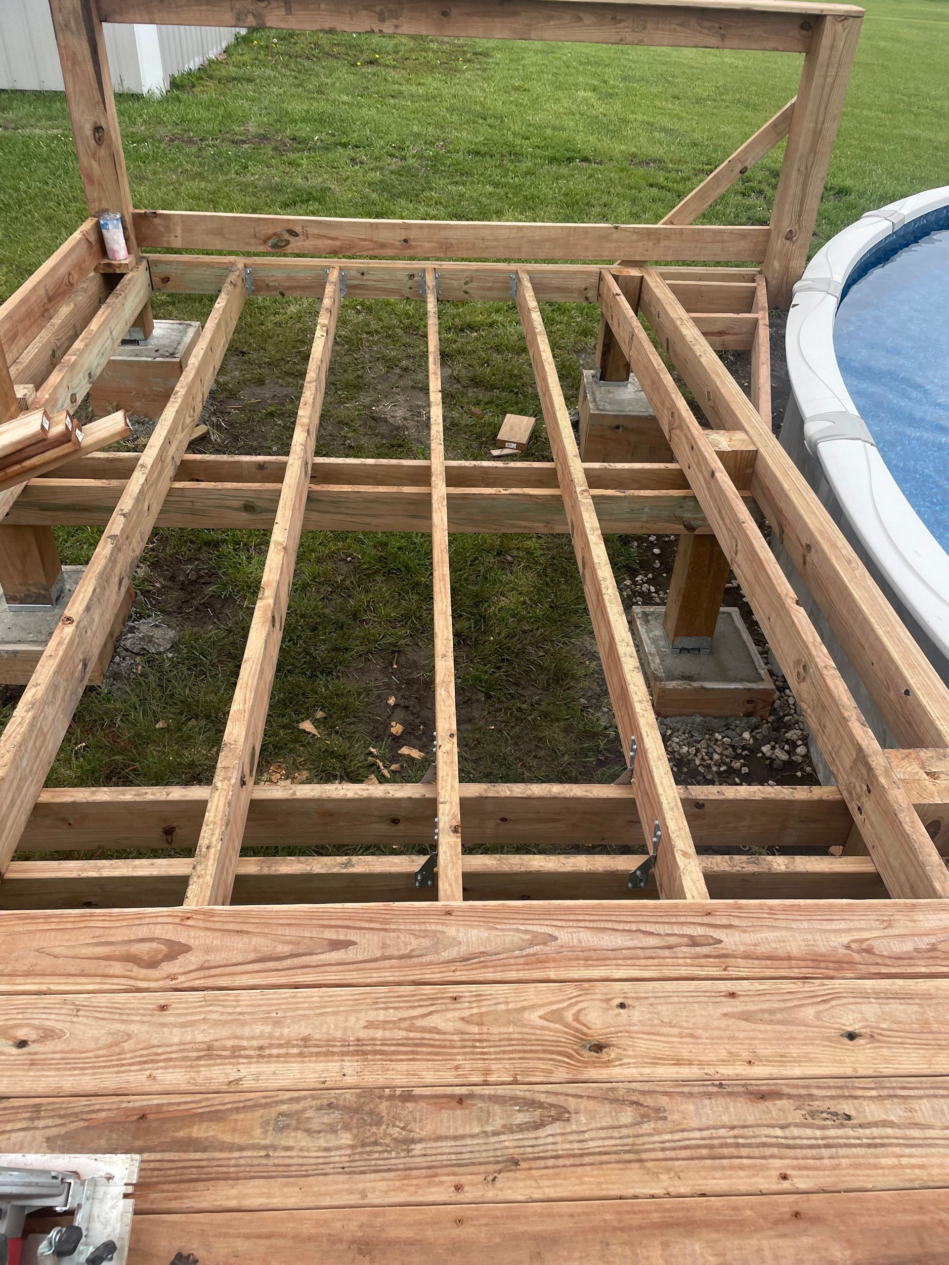 A wooden deck is being built next to a pool.