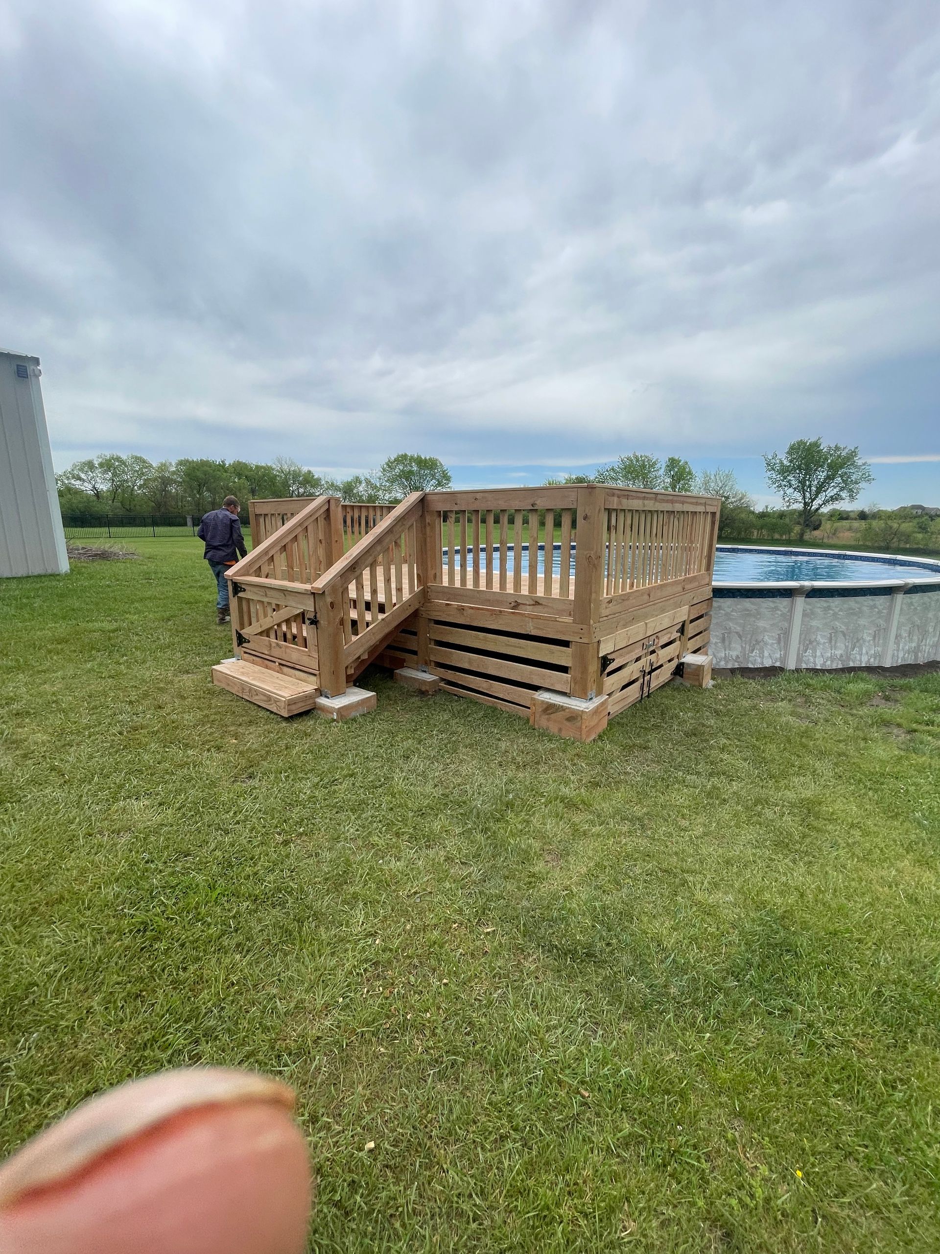 A person is holding a wooden deck next to a pool.