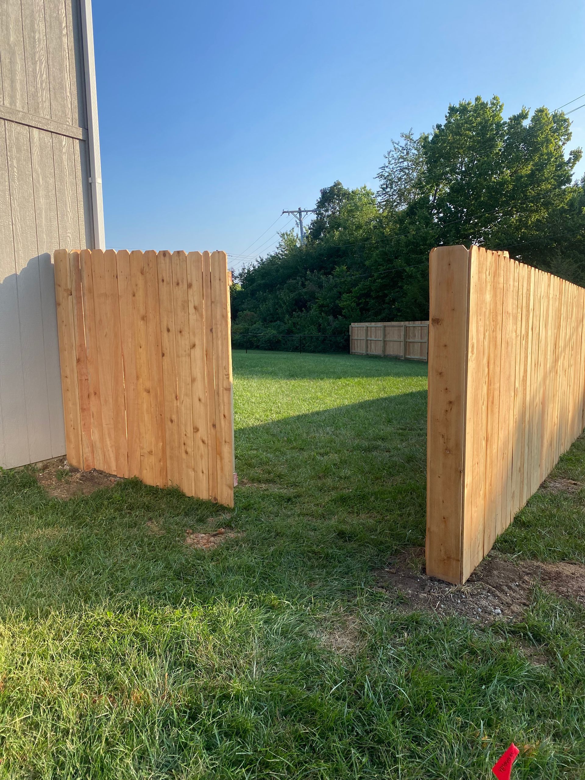 A wooden fence is sitting in the middle of a lush green field.