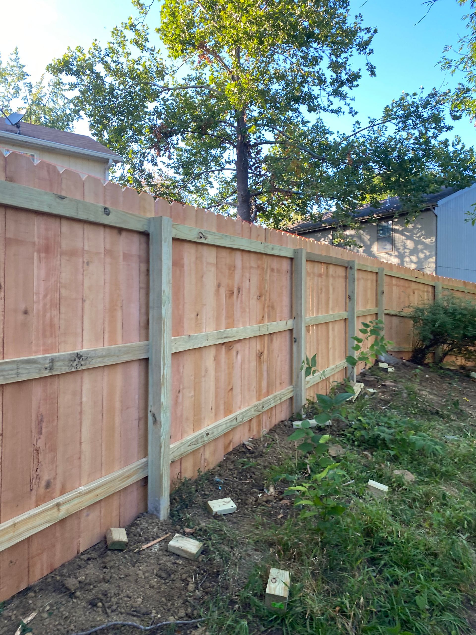 A wooden fence is being built in the backyard of a house.