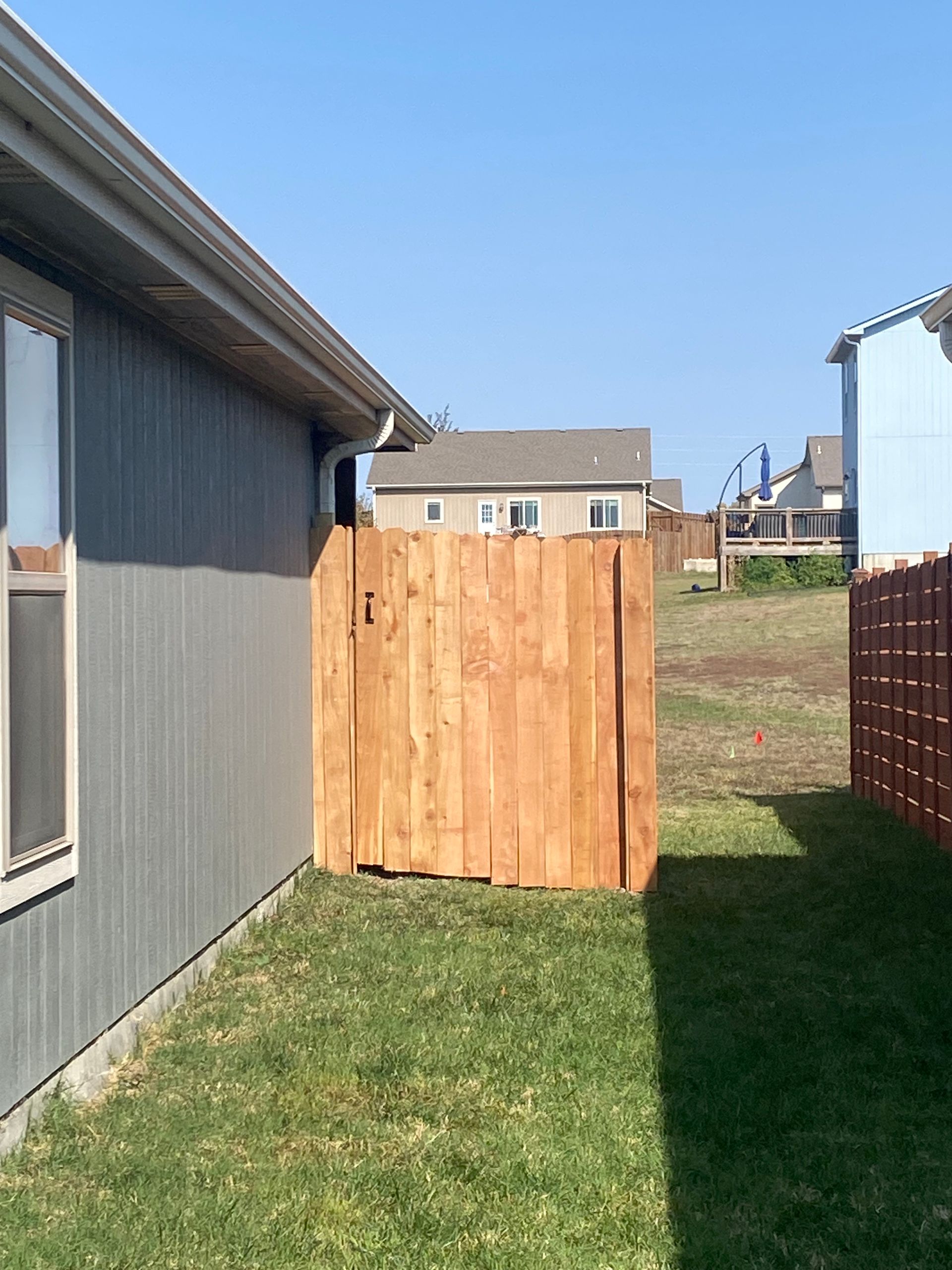 A wooden fence is in the backyard of a house.