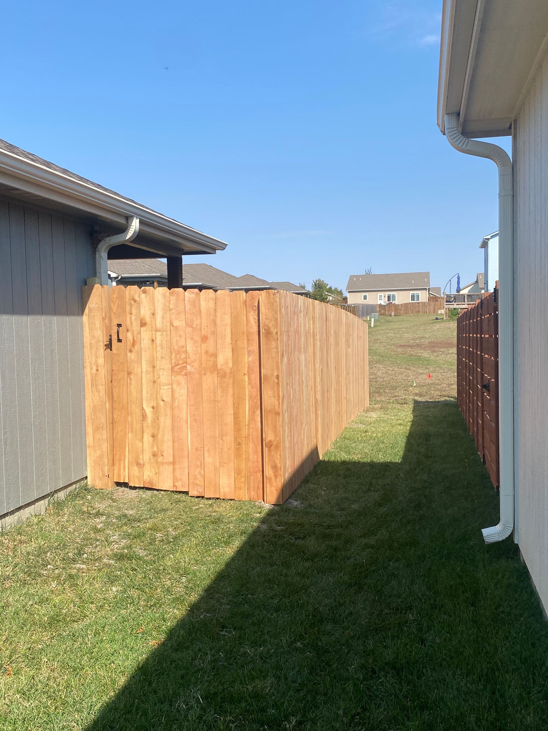 A wooden fence is in the backyard of a house.