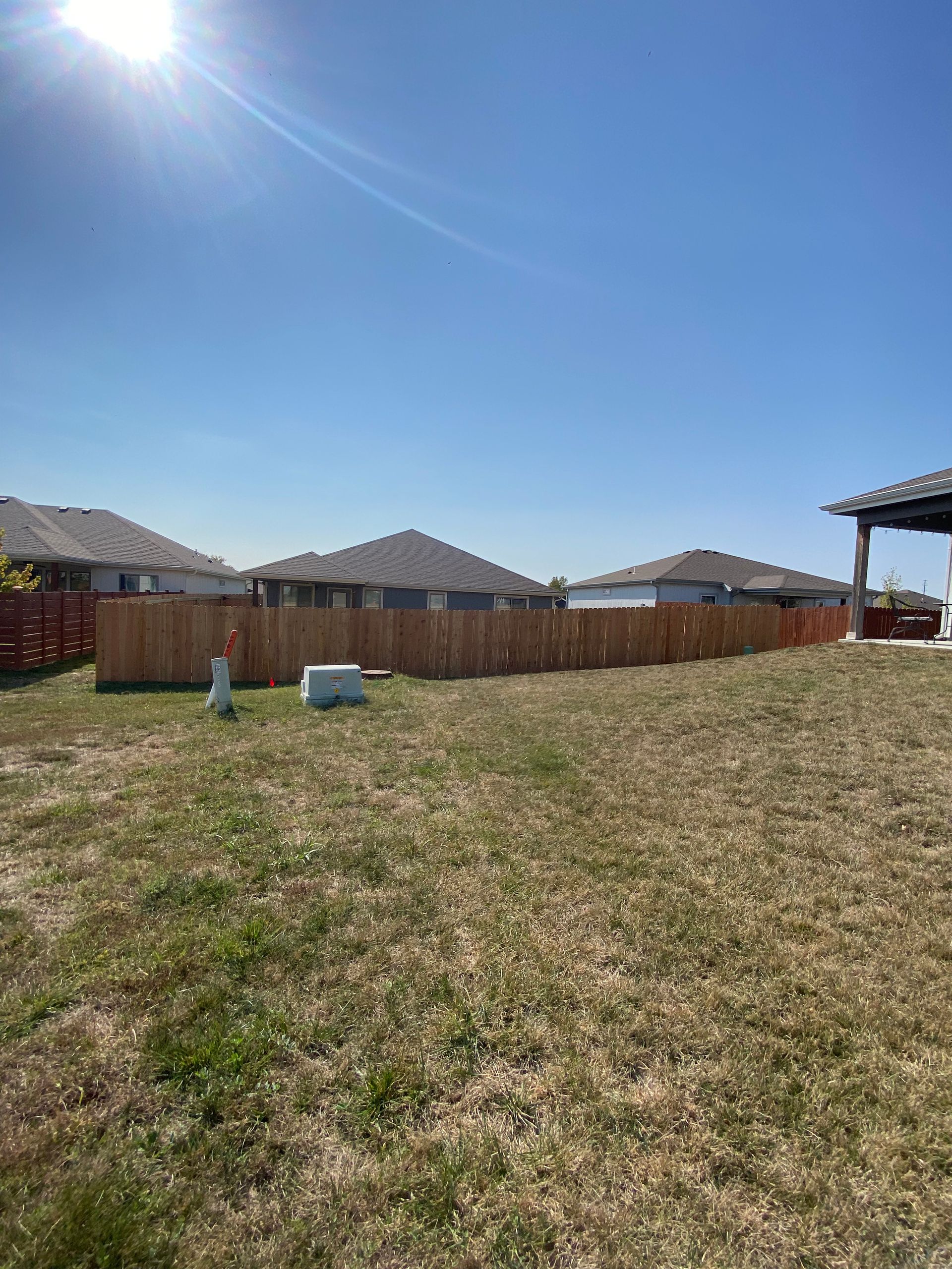 There is a wooden fence in the middle of a grassy field.
