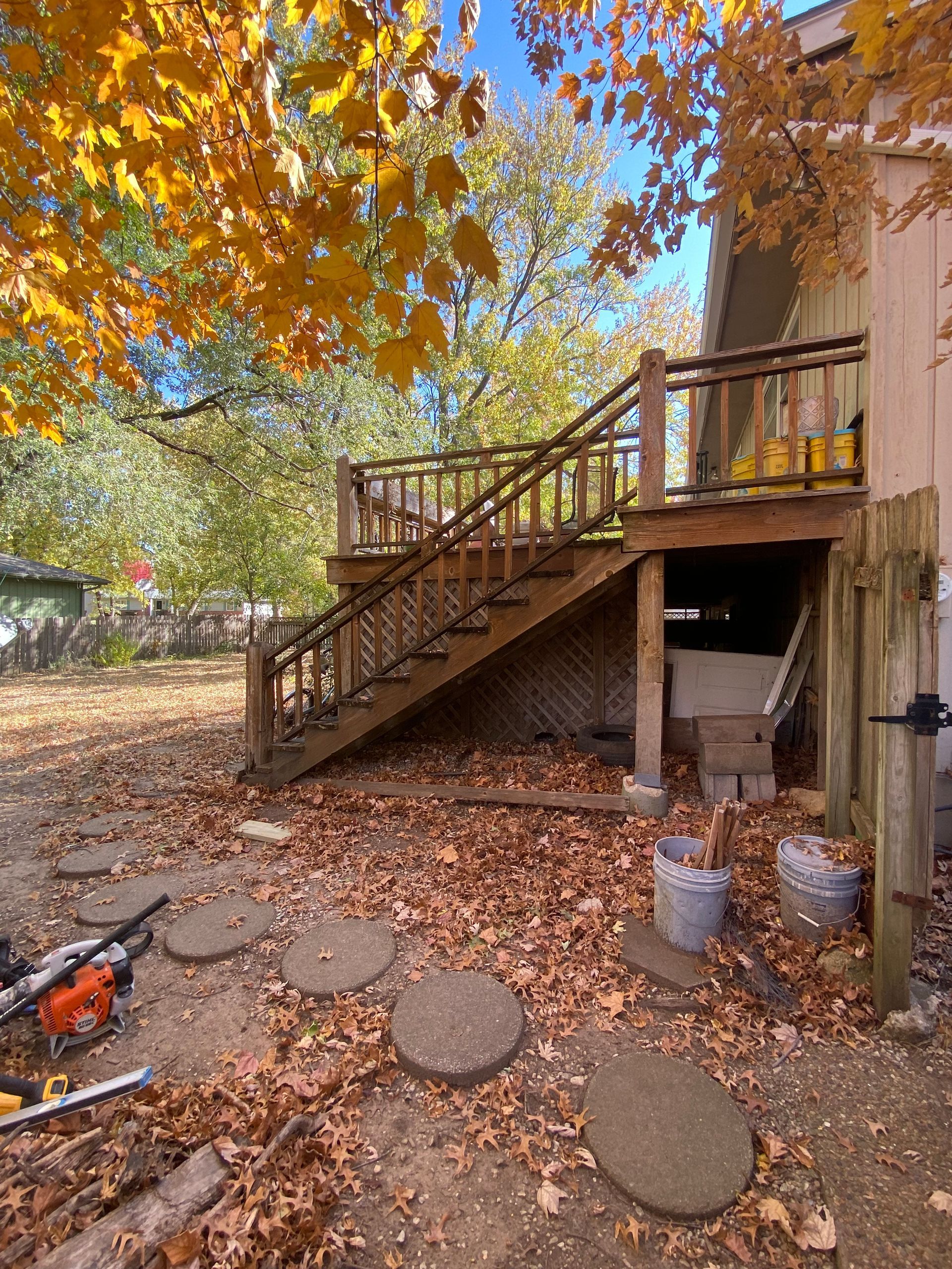 A wooden deck with stairs leading up to it is being built in the backyard of a house.
