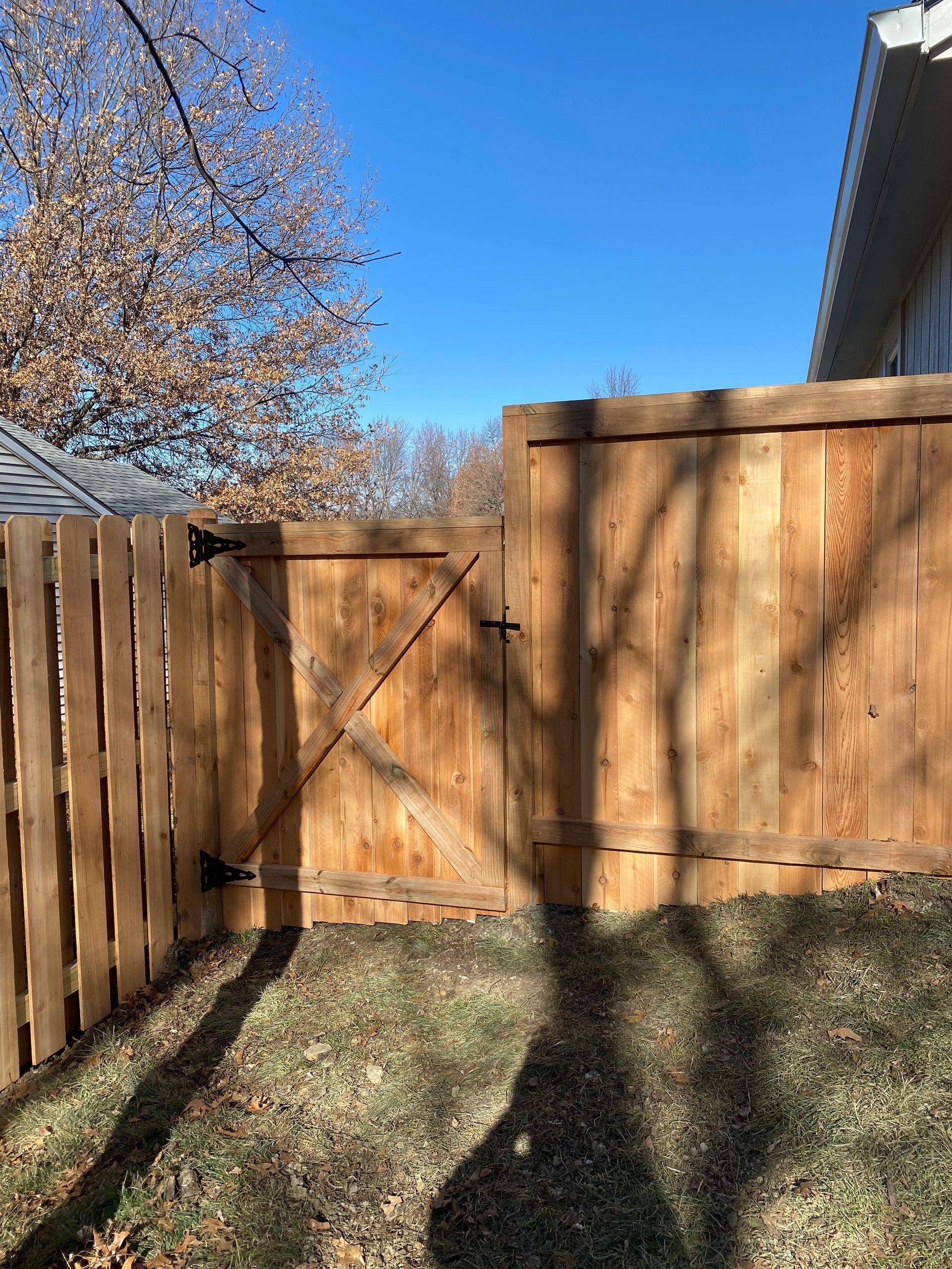 A wooden fence with a gate in the backyard of a house.