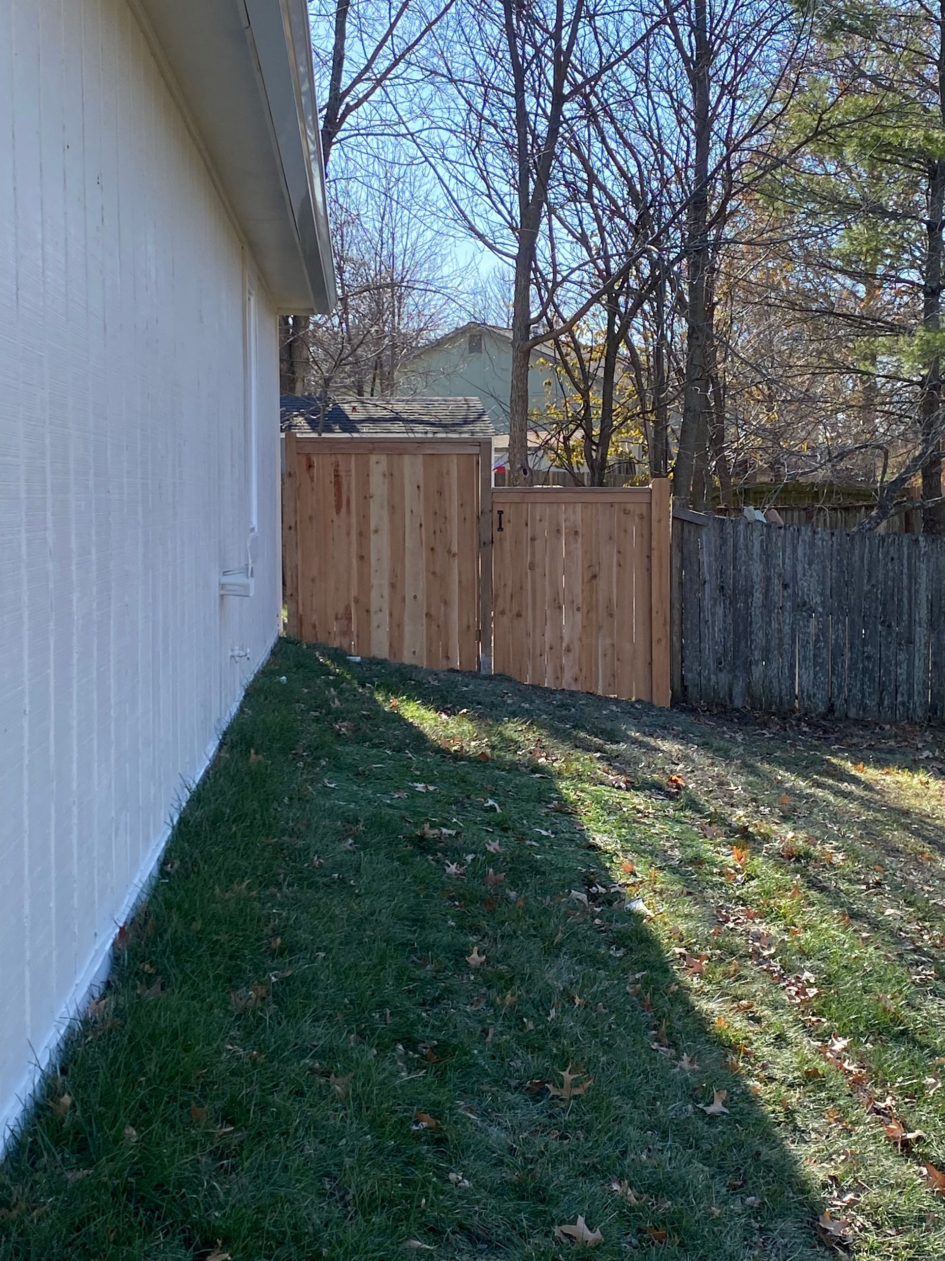 A white house with a wooden fence in the backyard.